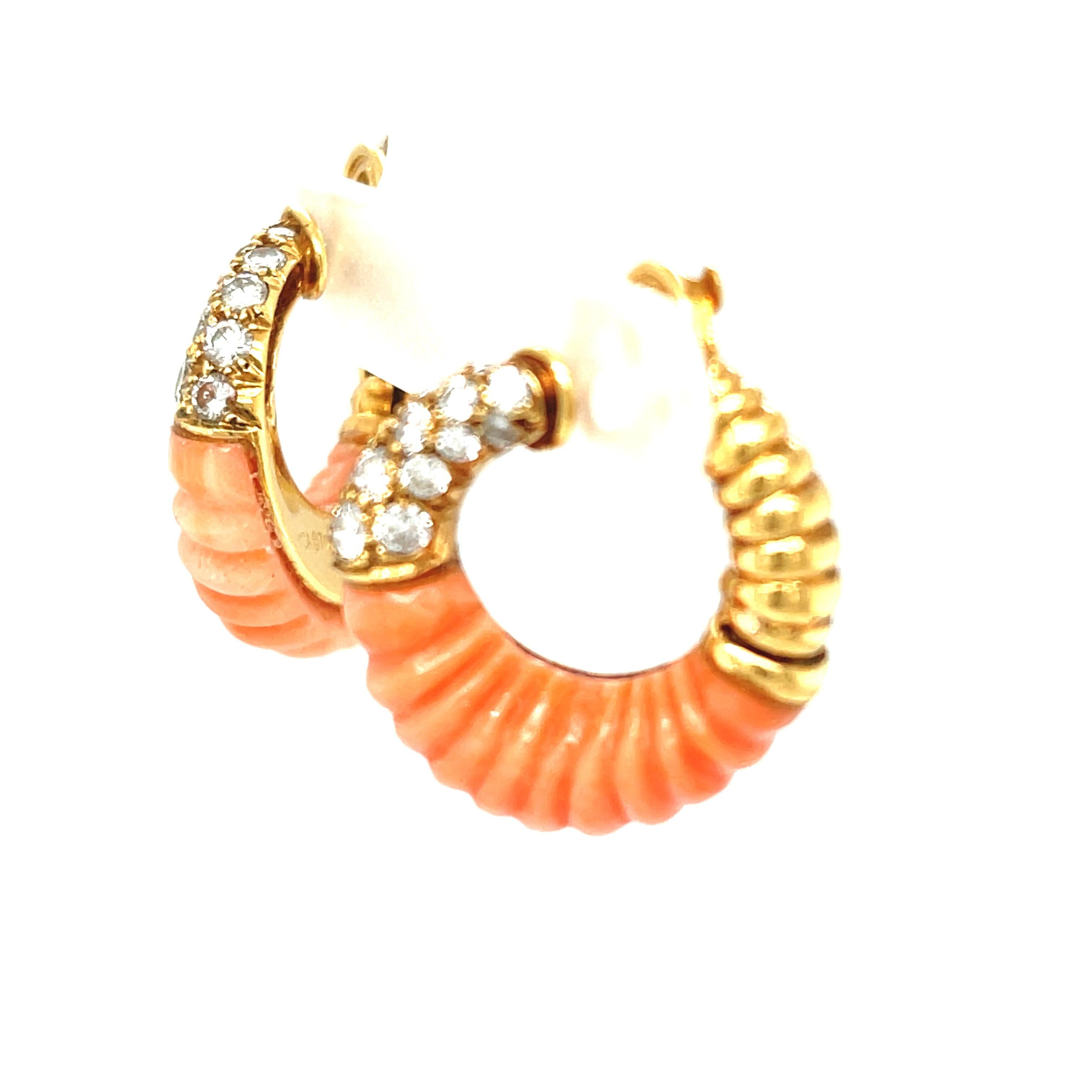 A vintage pair of fluted pink coral and diamond earrings by Van Cleef & Arpels, circa 1970. These creole style earrings fit the ear in a flattering way, as they are angled to show on the ear. The top of the earring is set with round brilliant