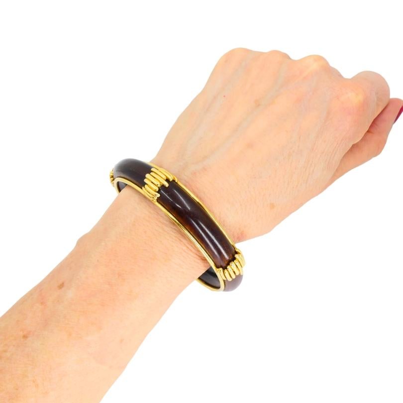 This vintage Van Cleef & Arpels bangle bracelet pairs rich natural wood with 18k yellow gold for a distinctive and refined look. 
The smooth wooden surface has a deep tone that highlights the bracelet’s sculptural form, while the gold edges and