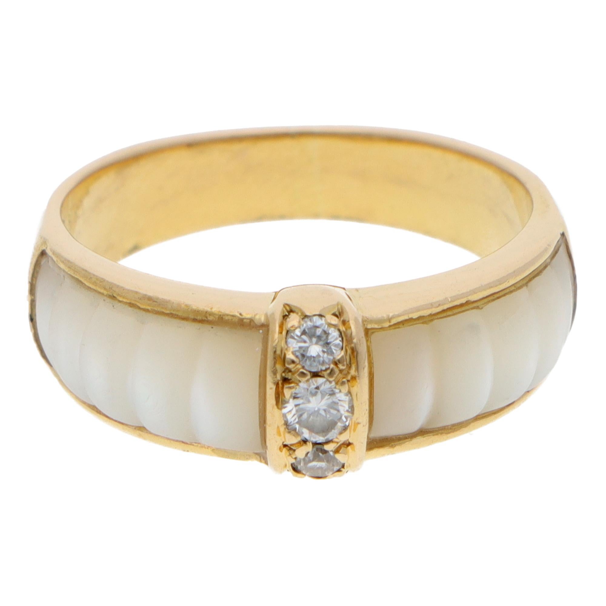 Magnifique bague vintage Van Cleef & Arpels en or jaune 18 carats, ornée de diamants et de coquillages blancs.

La bague est ornée de 3 diamants ronds de taille brillant et d'un magnifique coquillage blanc sculpté sur le côté. Elles sont reliées à