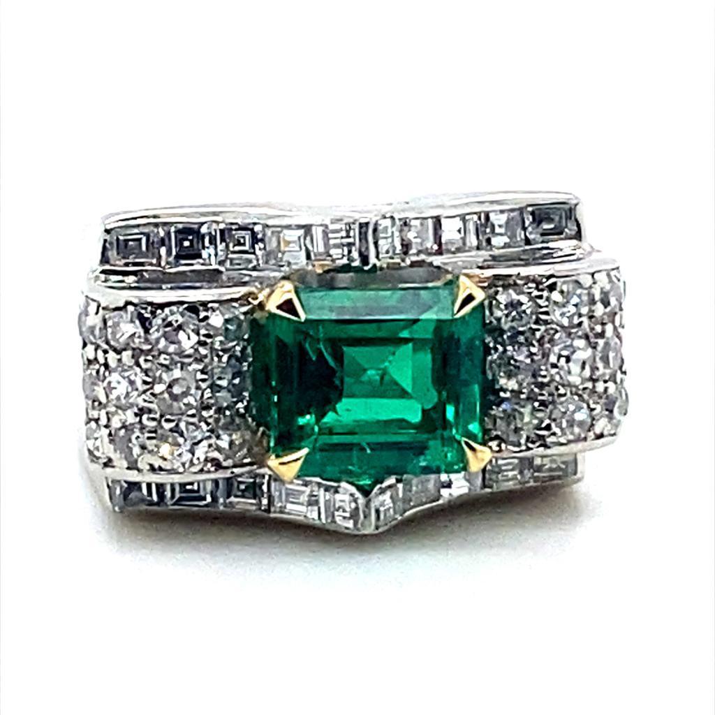 A Vintage Van Cleef & Arpels emerald and diamond platinum ring, circa 1940.

Set its centre with a Columbian emerald cut emerald of 2.07cts within four contrasting yellow gold claws within a stylized rectangular chunky platinum mount designed with