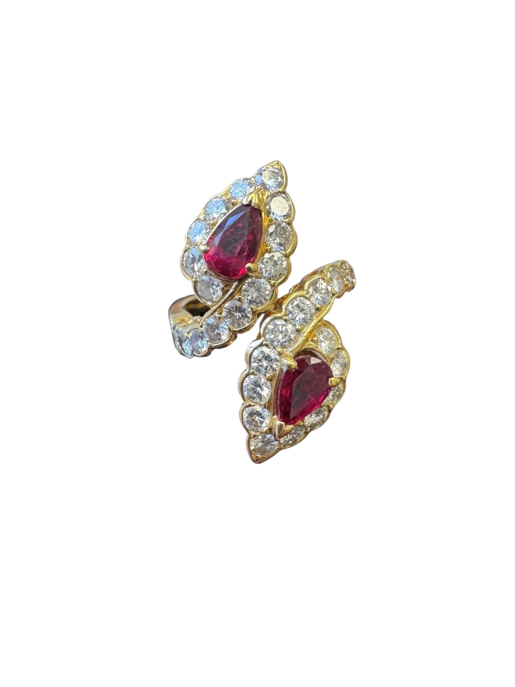 Une superbe et rare bague bypass vintage de Van Cleef & Arpels, réalisée en or jaune 18 carats. Cet élégant modèle présente deux rubis en forme de poire totalisant environ 1,03 carat, chacun encadré d'un halo festonné de diamants ronds brillants.