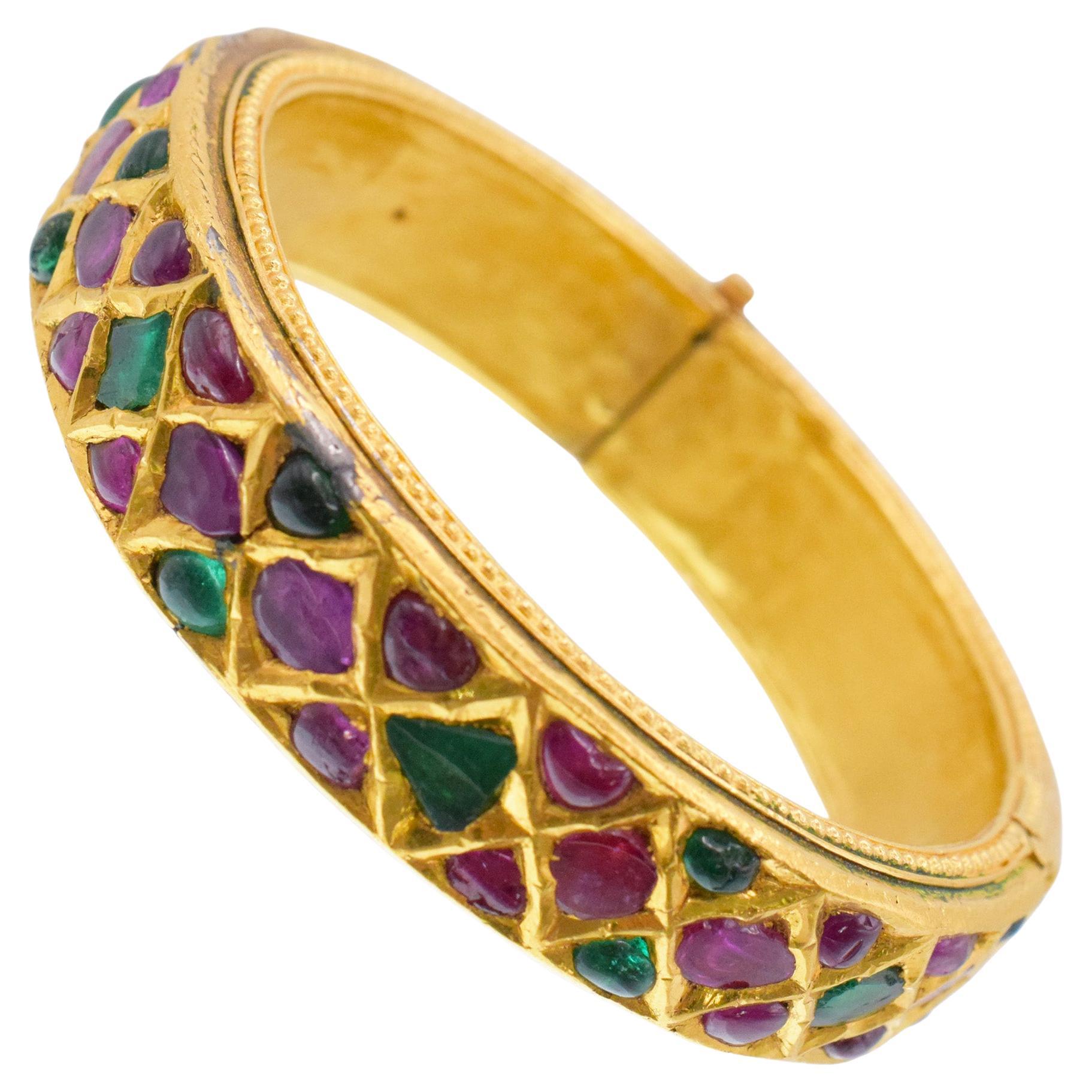 Van Cleef & Arpels Ruby And Emerald Bracelet In 18k Yellow Gold. Circa 1964; This yellow gold bangle bracelet is set throughout with cabochon and mogul
cut rubies and emeralds of different shapes; Equipped with hinged lock. Inscribed: VCA . Stamped: