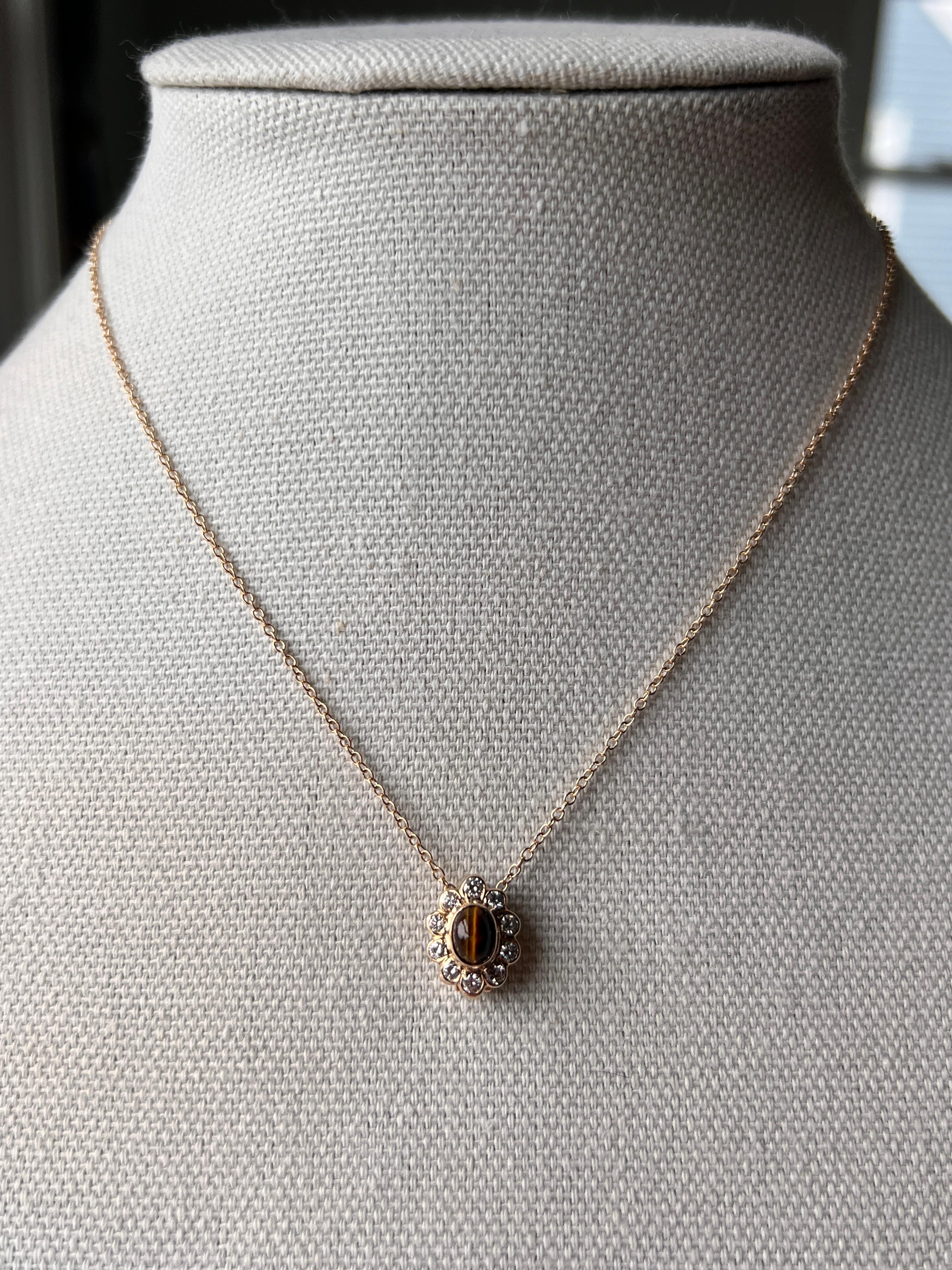 Un pendentif vintage Van Cleef & Arpels en or jaune 14 carats serti d'un magnifique œil de tigre ovale de 4,35 x 5,90 mm en son centre. Ce pendentif est entouré de dix diamants ronds et brillants totalisant environ 0,50 carats, de couleur G et de