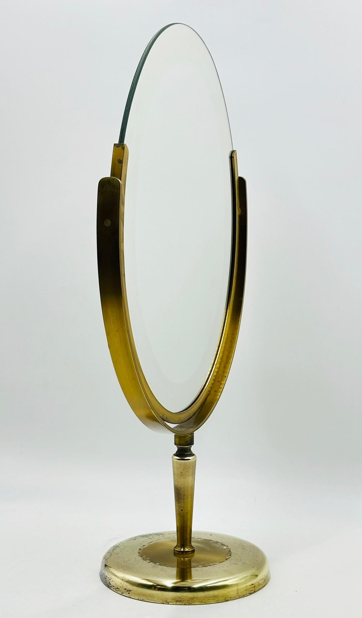 Miroir de courtoisie en laiton conçu et fabriqué dans les années 1960 par Charles Hollis Jones.

La pièce est dotée d'un miroir ovale à deux côtés, mais aucun des deux côtés n'est grossissant.

Le miroir est dans son état d'origine et peut être