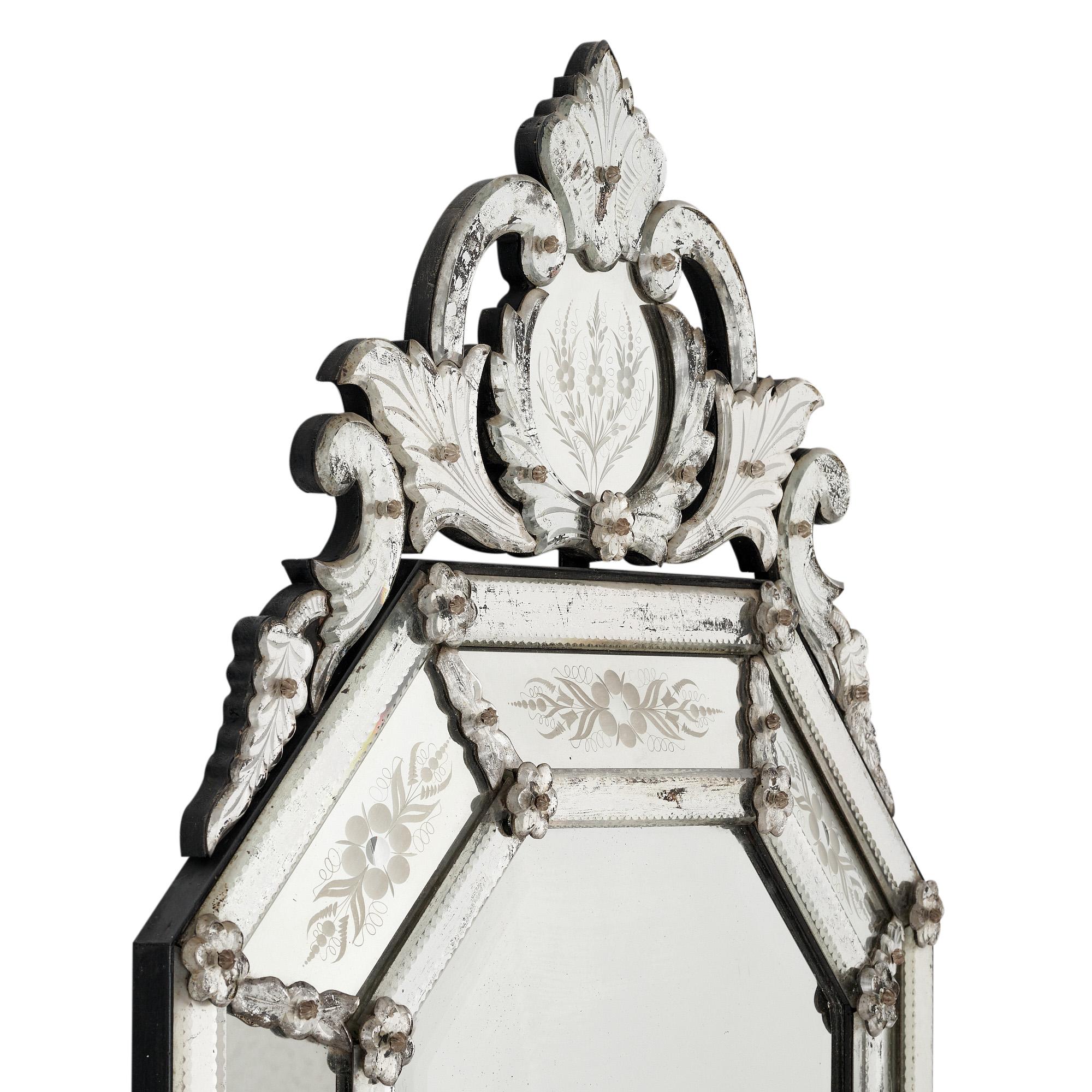 Vintage Venetian mirror with lovely fronton and engraved floral designs. The central mirror has an elongated octagonal shape. The cushion mirror style is complimented by the beautiful patina of the mirror. Glass rosettes secure the mirrors. A