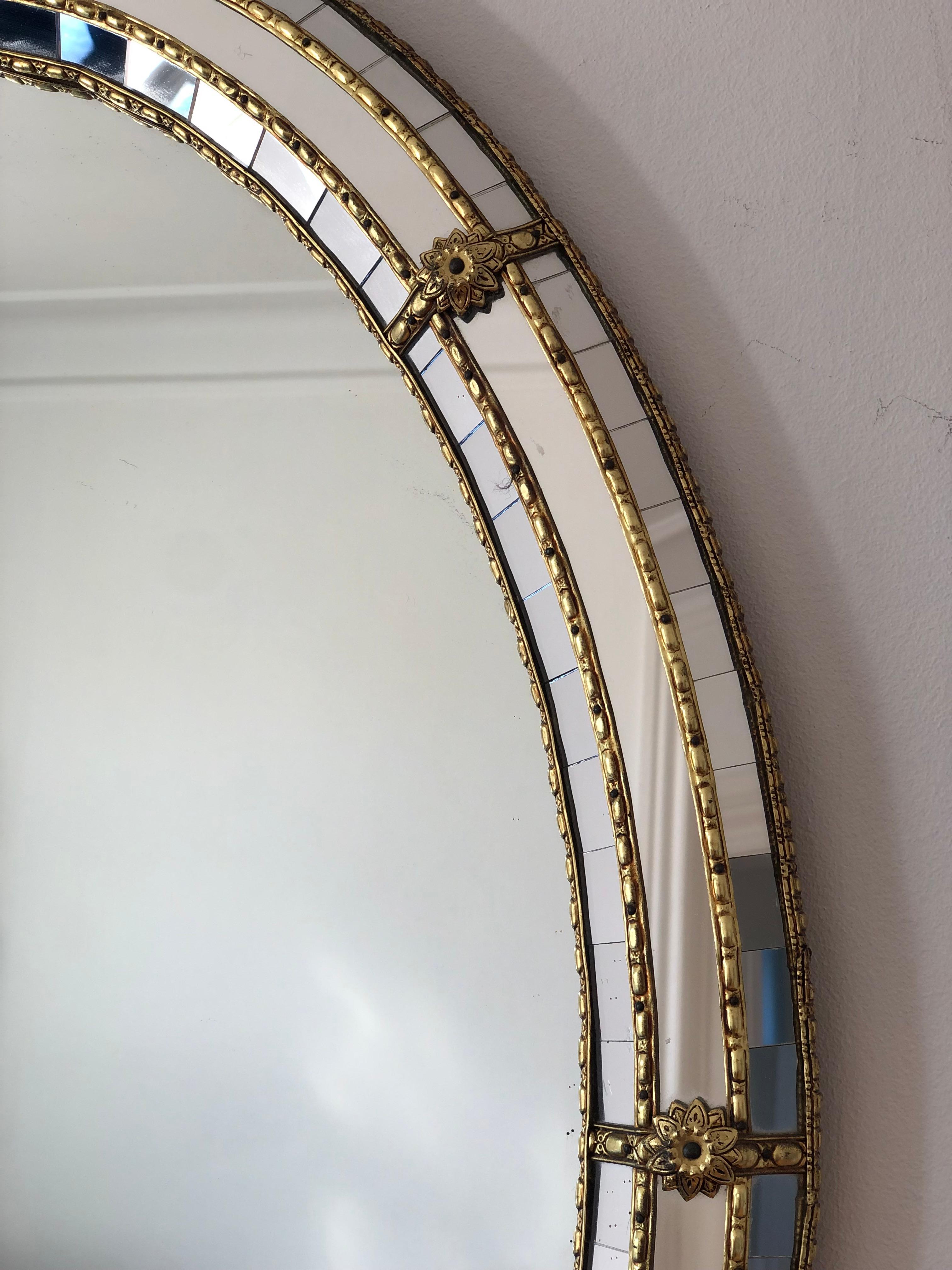 A Vintage Venetian oval mirror in Spanish style, dating back to the 1990s.
The frame is beautifully hand-crafted and decorated with small crystals on the outer and inner edges, with larger crystals running along the center. The elegant brass strip