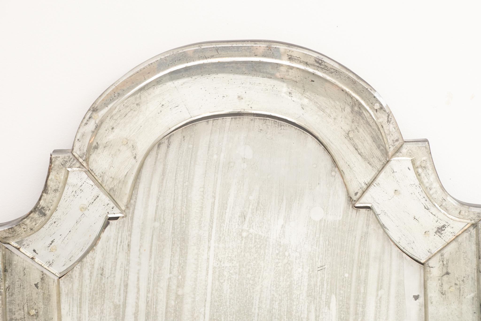 The Venetian-style wall mirror, shown here, was made in the 1940s. Featuring an antiqued mirror center pane, the piece is distinguished by its arched top design, and wide mirrored-glass border. Perfectly proportioned for an entry way, powder room or