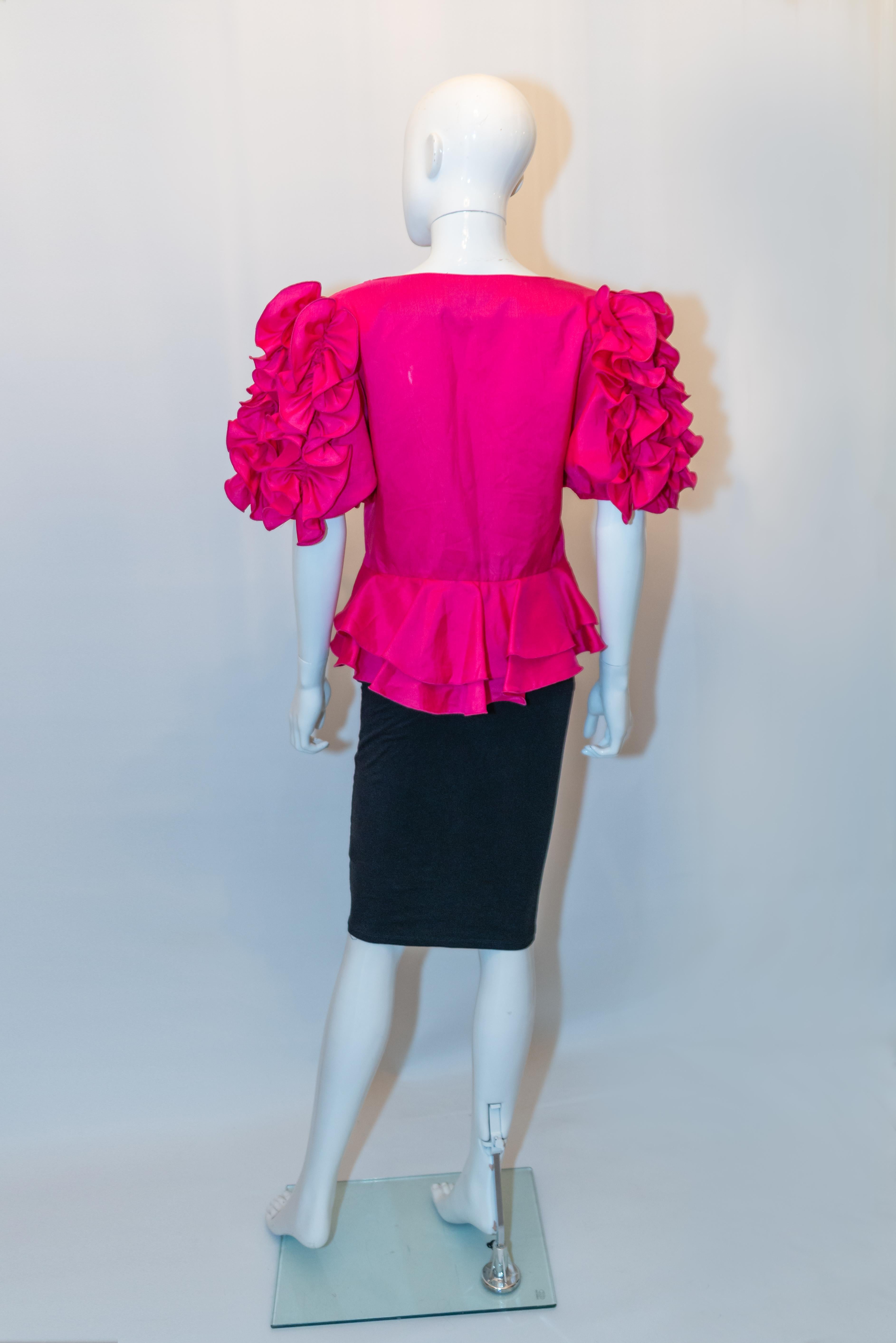 A pretty vintage pink party top by Vera Mont. The top has wonderful detail on the sleaves, a button front opening with covered buttons. It has a peplum at the back , and is lower at the back than the front. Size I48, UK size 16 , old size