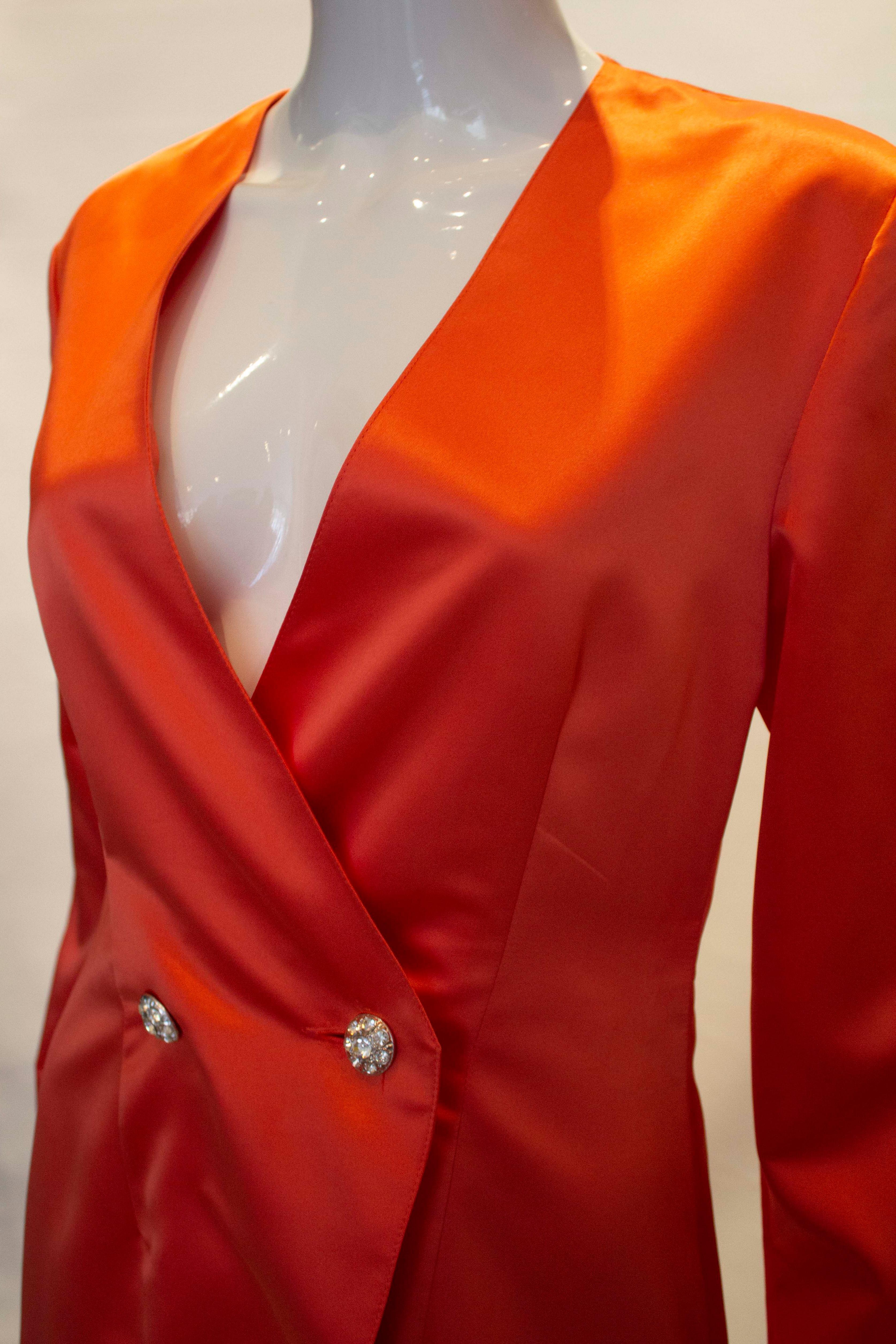 A head turning evening jacket by Vera Mont. The jacket is in a pretty salmon pink colour with a two button diamante fastening. It has a v neckline, with a slit at the back and is fully lined.
