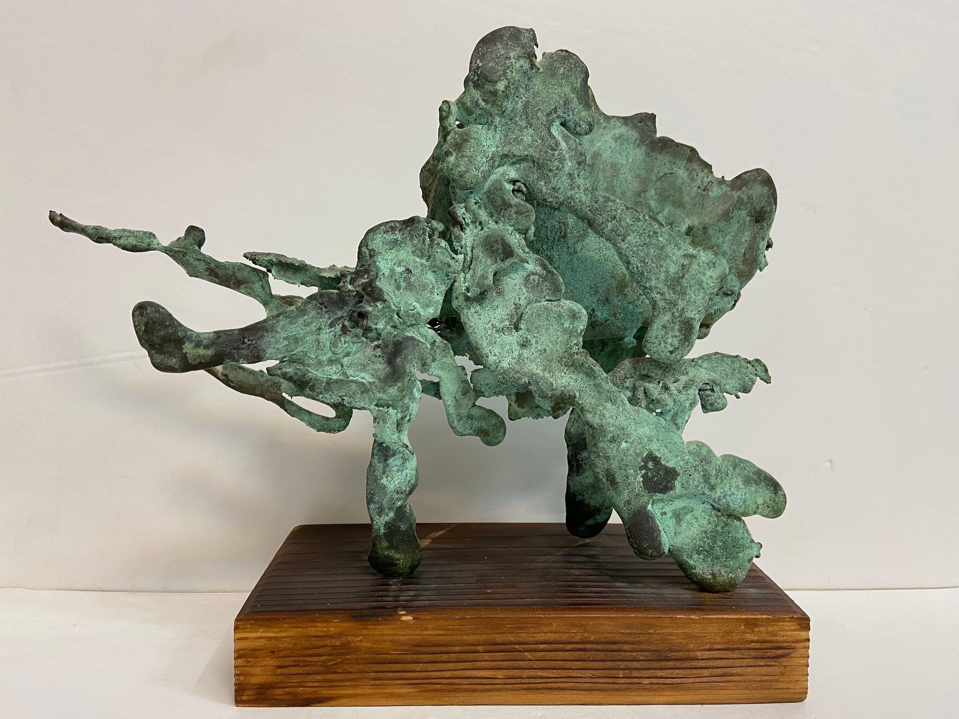A vintage, circa 1960's, large spill cast bronze brutalist style sculpture with verdigris patina on a wood base. The process of the casting evokes a feeling of movement and freedom, captured in a moment. The wood base itself measures approximately