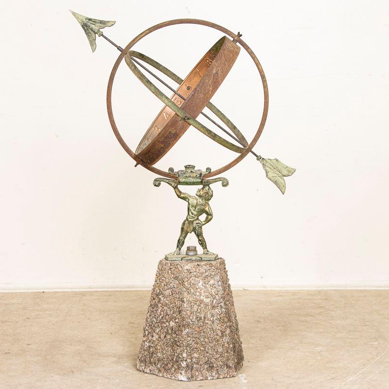 Antique garden ornament from Denmark, known as a Sun Clock or Armillary, with a cast metal figure holding spherical rings (representing Atlas holding up the world) and mounted on a pedestal base. The metal of this sun clock has an aged green