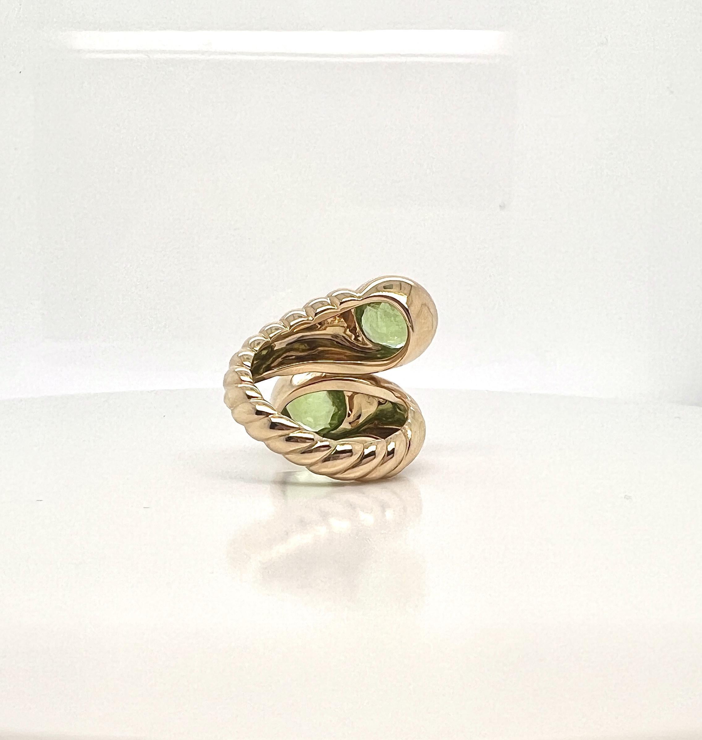 Anello Bypass con peridoto in oro 18k di Verdura. 

Realizzato in oro 18 carati e incastonato con due vibranti gemme di peridoto a taglio rotondo. L'audace fascia d'oro ritorta aggiunge un tocco di glamour retrò, rendendolo l'anello bypass perfetto