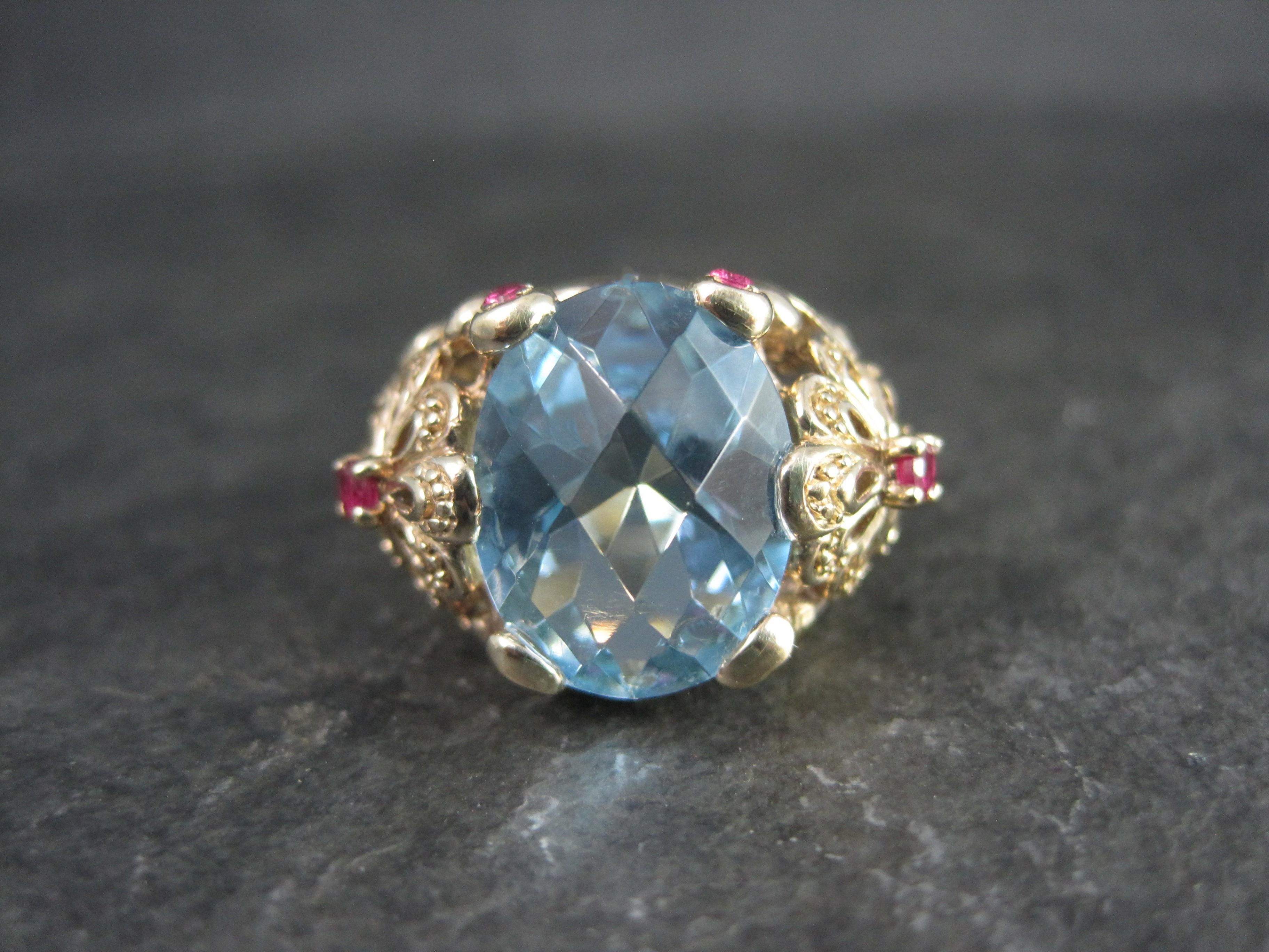 This stunning estate ring is gold vermeil over sterling silver.
It features an 11x14mm faceted blue topaz accented by 6 rubies.

The face of this ring measures 9/16 of an inch north to south with a rise of 9mm off the finger.
Size: 8

Marks: A,