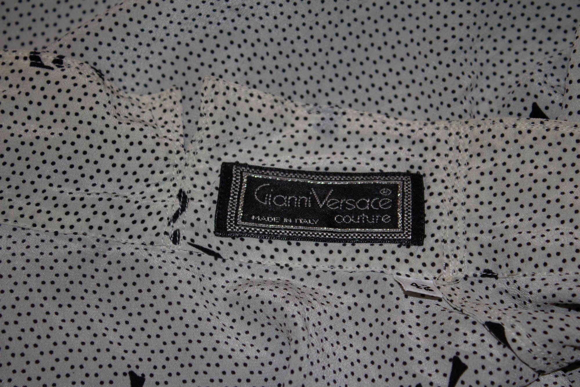 Un joli chemisier vintage de Gianni Versace Couture,. Dans un blanc doux avec un imprimé de nœuds noirs, la blouse a un col cravate et des poignets boutonnés.  Taille EU italienne 42, mesures : Poitrine 38/9'', longueur 26''