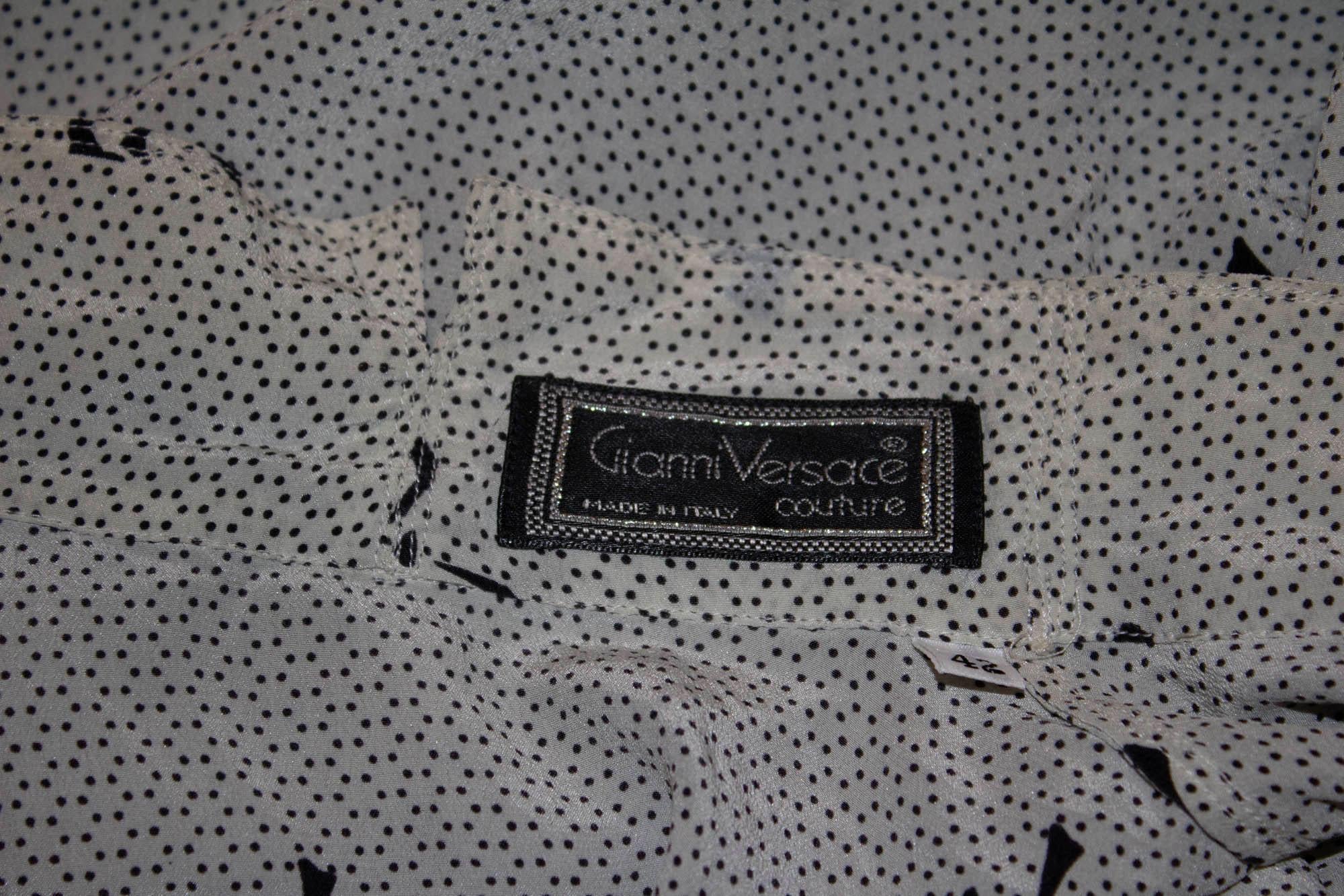 A pretty vintage blouse by Gianni Versace Couture,. In a soft white with black bow print , the blouse has a tie neck and button cuffs.  Size EU Italian 42, measurements: Bust 38/9'', length 26''