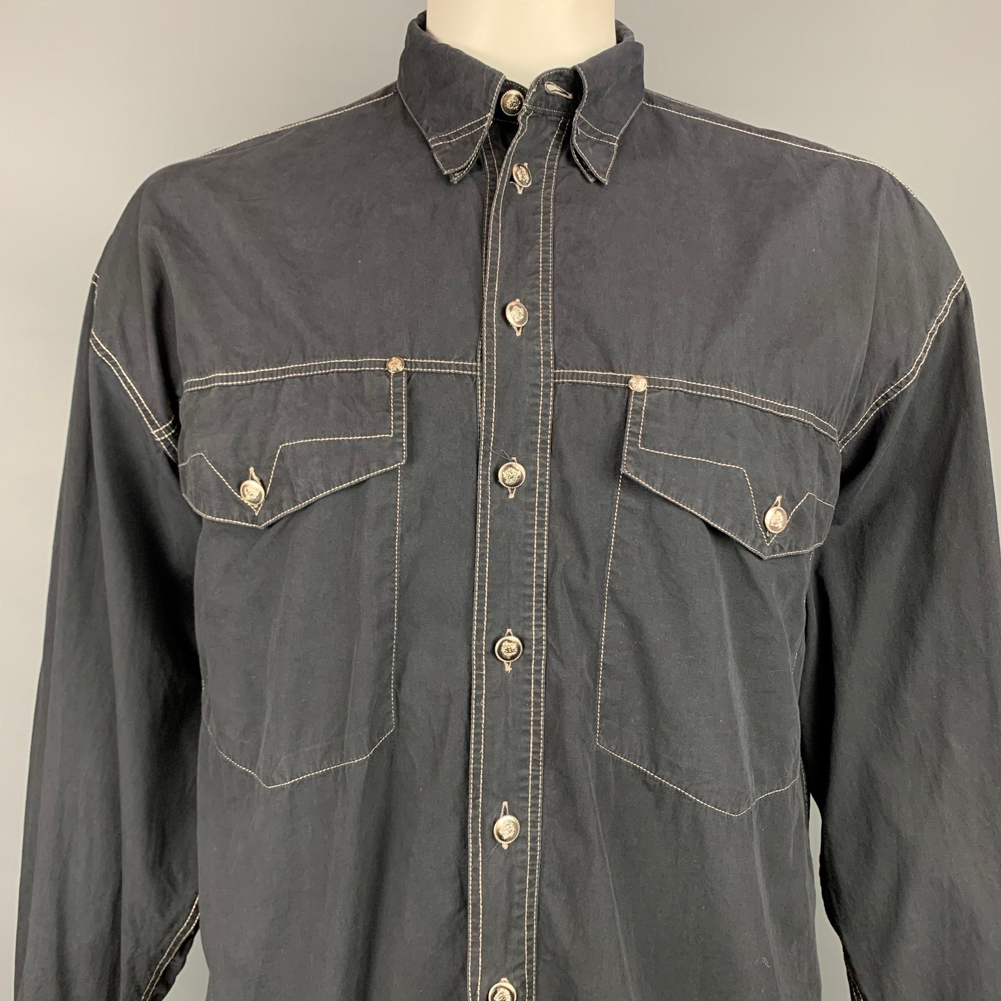 Vintage VERSACE JEANS COUTURE long sleeve shirt comes in a black cotton with contrast stitching featuring a button down style, loose fit, patch pockets, and silver tone medusa head buttons. Made in Italy.

Good Pre-Owned Condition.
Marked: