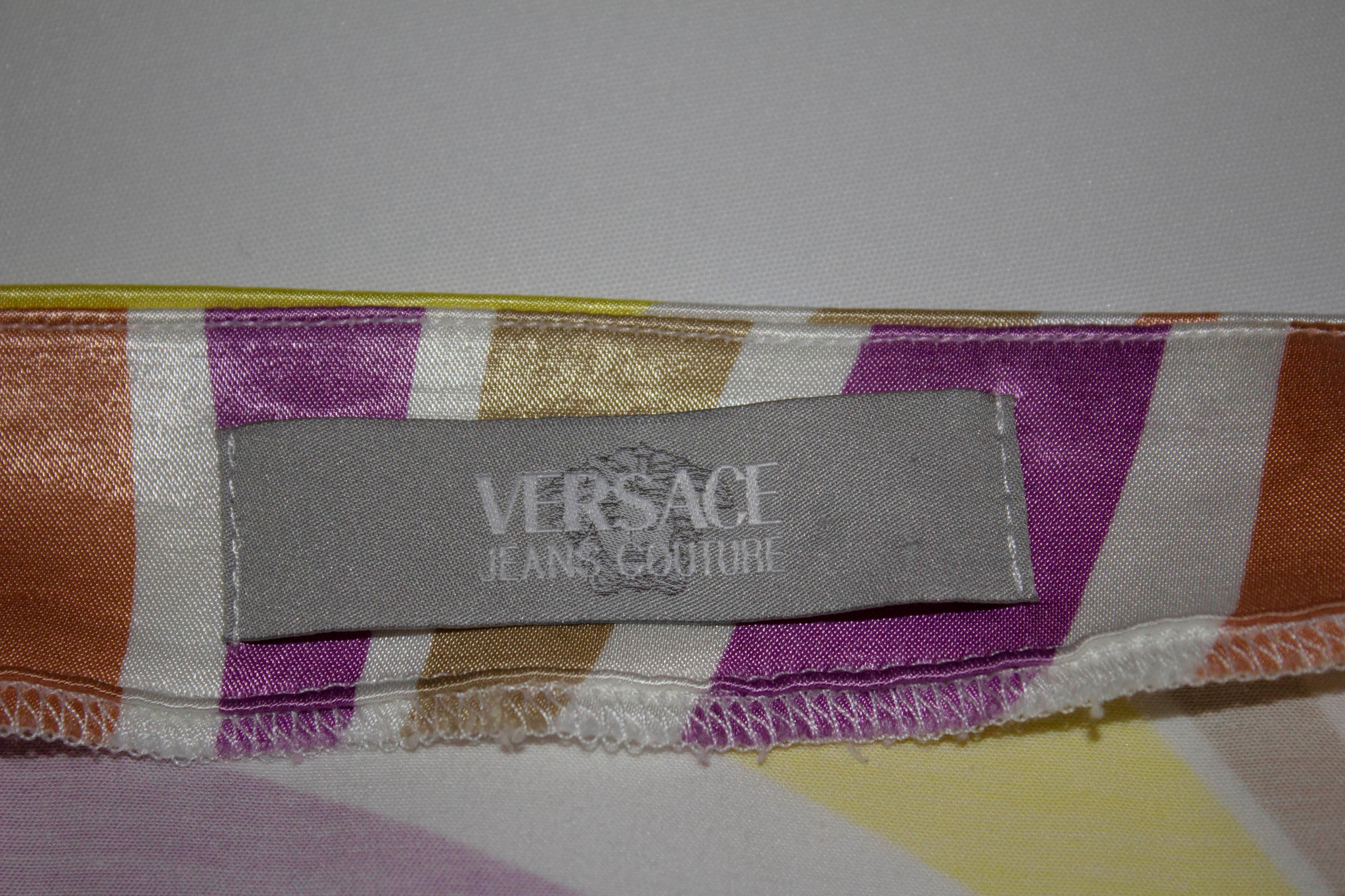 Une jupe d'été amusante de Versace, ligne Jeans Couture.  Sur  un mélange de coton, et un magnifique imprimé multicolore, la jupe a une ouverture zippée sur le côté et une fente de 11,5 cm  sur le côté gauche.

Etiqueté taille 32/46 , mesures ;
