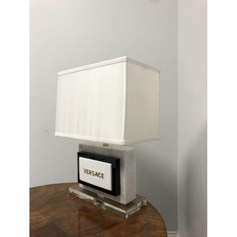 A Contemporary Modern style Marble and Acrylic Lamp by Versace. Single standard bulb socket and 3-way rotary switch. Includes shade.

Measures: Base: 11.25w 4.5d, Shade: 13.5w 8d 9.5h, Overall Height to Top of Finial: 19.5

Excellent condition. In
