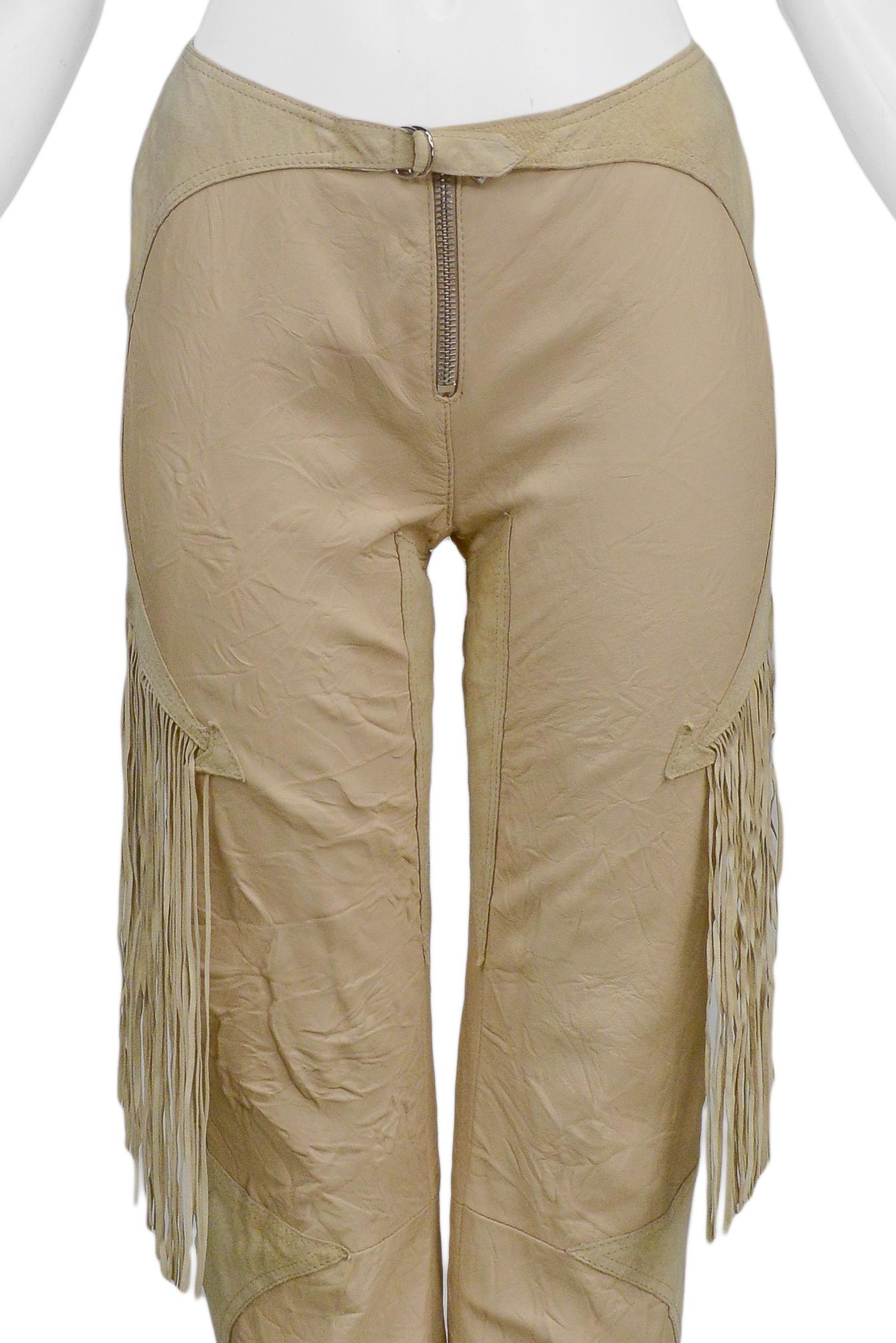 Resurrection Vintage is excited to offer a pair of vintage Versace tan crinkle leather pants featuring an exposed silver-tone center front zipper, attached yoke with buckle, fringe at the sides and back, arrow inserts, ankle zippers, and tan lining.