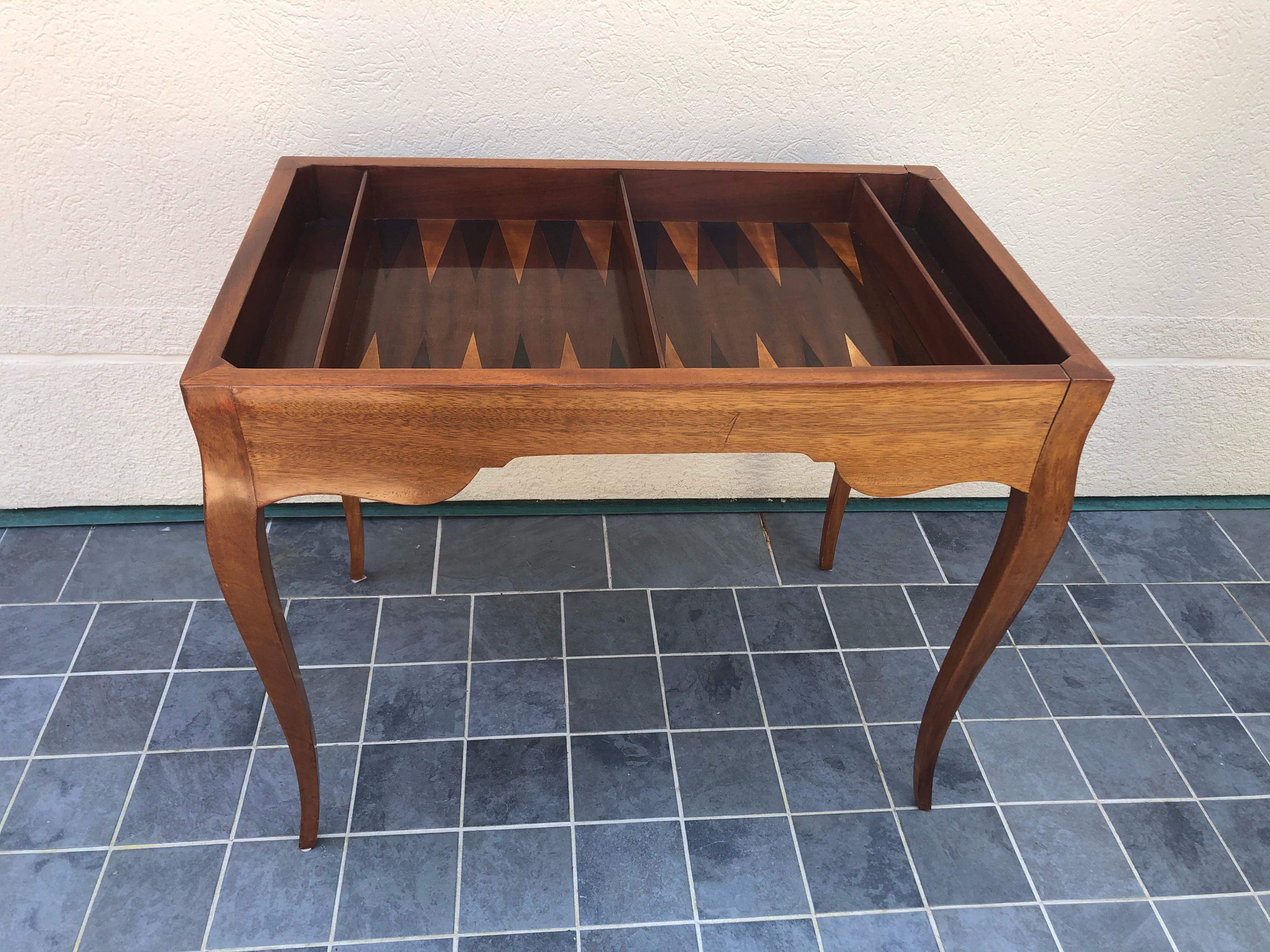 Fabulous game table crafted from a mix of woods in a rich walnut finish. Table features a chess or checkers inlay on a removable top and a backgammon board on the interior. It also has a green felt top for playing cards. The top has a raised edge on