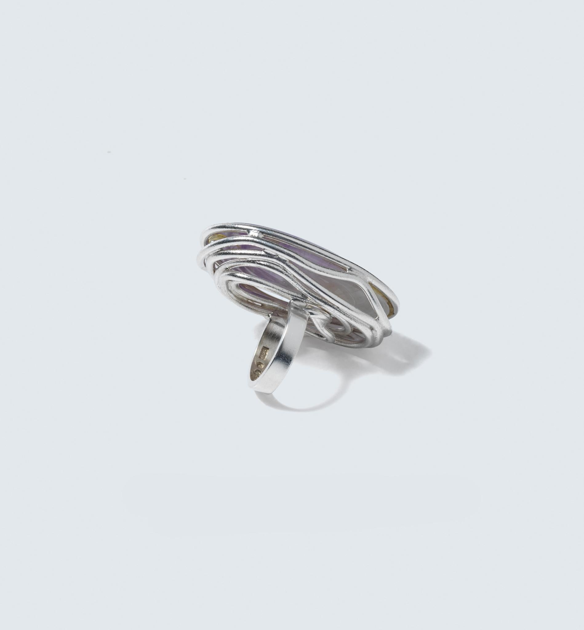 Dies ist ein großer und auffälliger Ring mit einem großen ovalen Amethysten im Cabochon-Schliff als Herzstück. Der Amethyst ist auf einzigartige Weise mit Silberdrähten gefasst, die sich um seinen Rand winden. Diese Drähte sichern nicht nur den