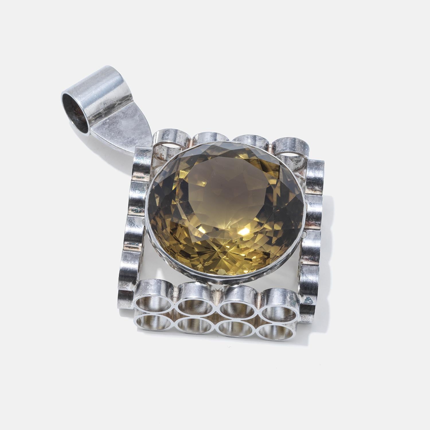 This silver pendant showcases an exceptionally large citrine gemstone, radiating with a deep, honey-like color that's both warm and captivating. The citrine is faceted into a round shape that maximizes its brilliance and fiery hues. Surrounding the
