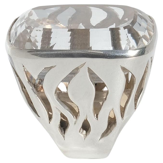 This amazing silver ring is adorned with a large rectangular cut rock crystal. Its prominent setting and shank are decorated with an openwork pattern which looks like flames of fire.

The ring looks like a piece of jewelry that could have been worn