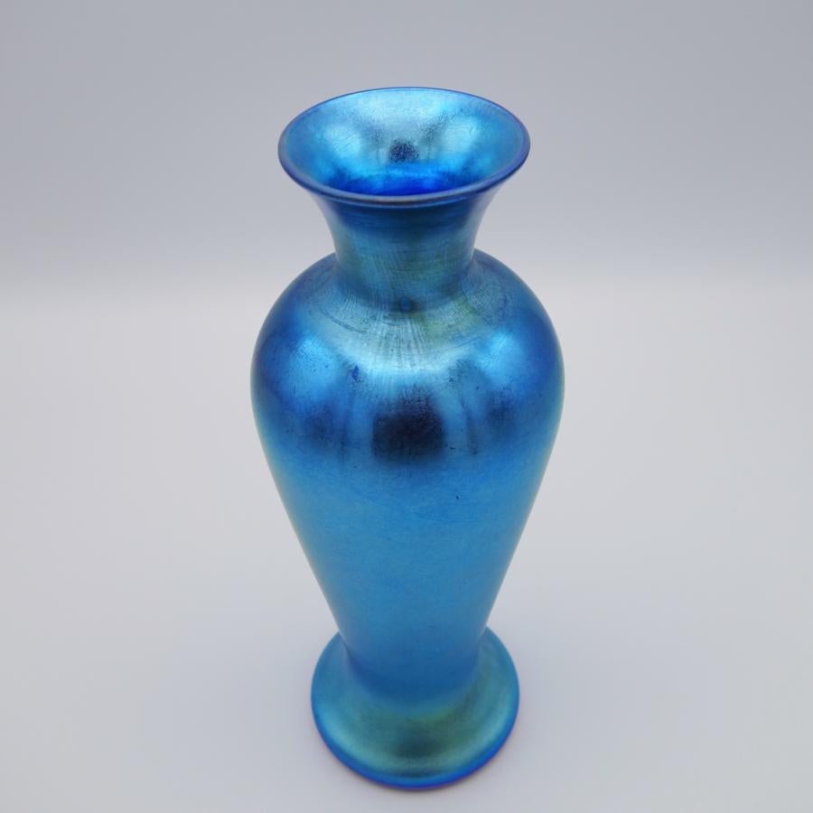 Offering this gorgeous Durand art glass iridescent blue vase. This vase features a curvaceous tapered cylindrical body with a flared lip. Signed on the underneath 