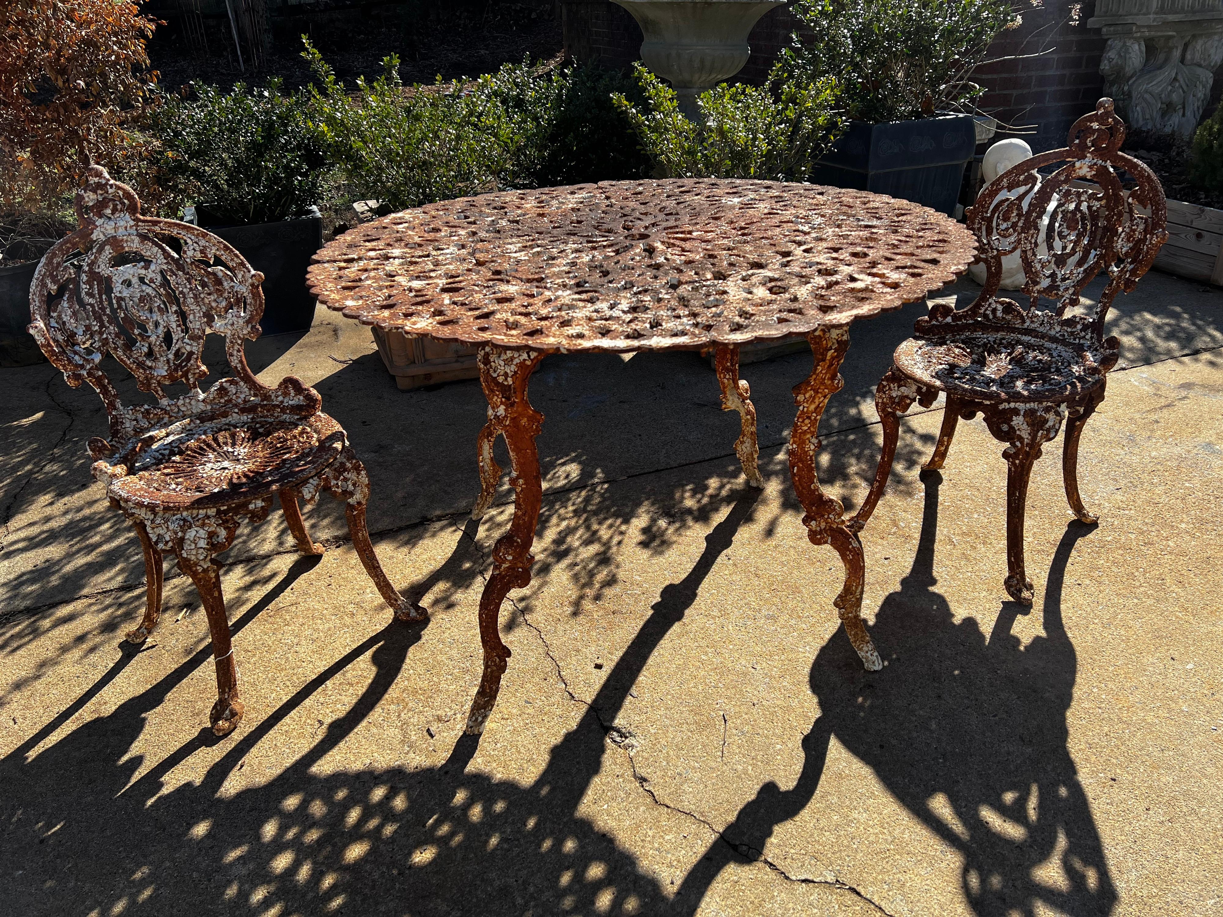 Antique Garden/Patio set with table and two chairs. Gorgeous natural patina that would be hard to mimic so we have left them as is. 

Decorative pattern with dolphin legs on the table. Price is for the full set.

Chairs and table all sturdy and
