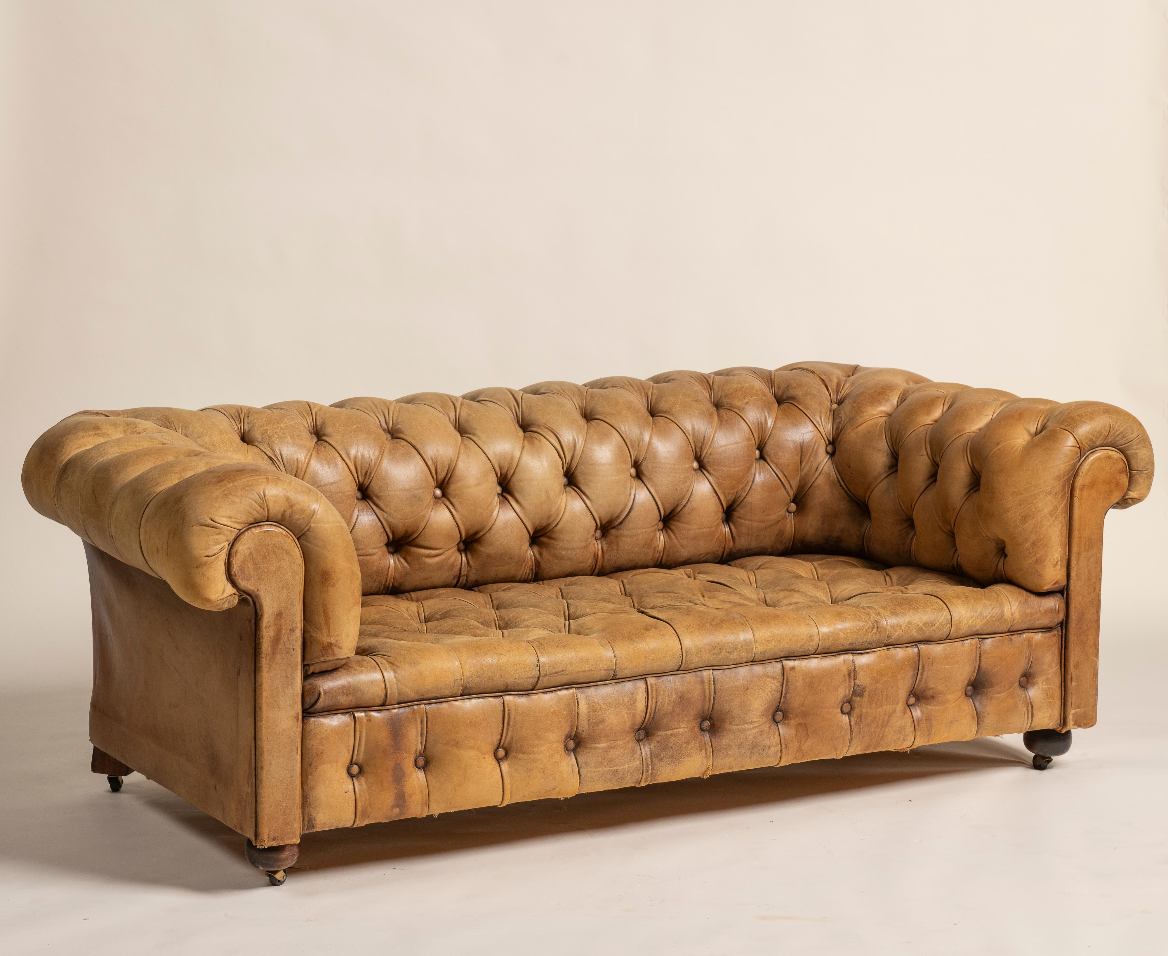 Un classico divano Chesterfield vittoriano in pelle color tabacco che offre tre comodi posti a sedere, offrendo stile e raffinatezza. La pelle lavorata è invecchiata con grazia, sviluppando una ricca patina che aggiunge carattere e fascino a