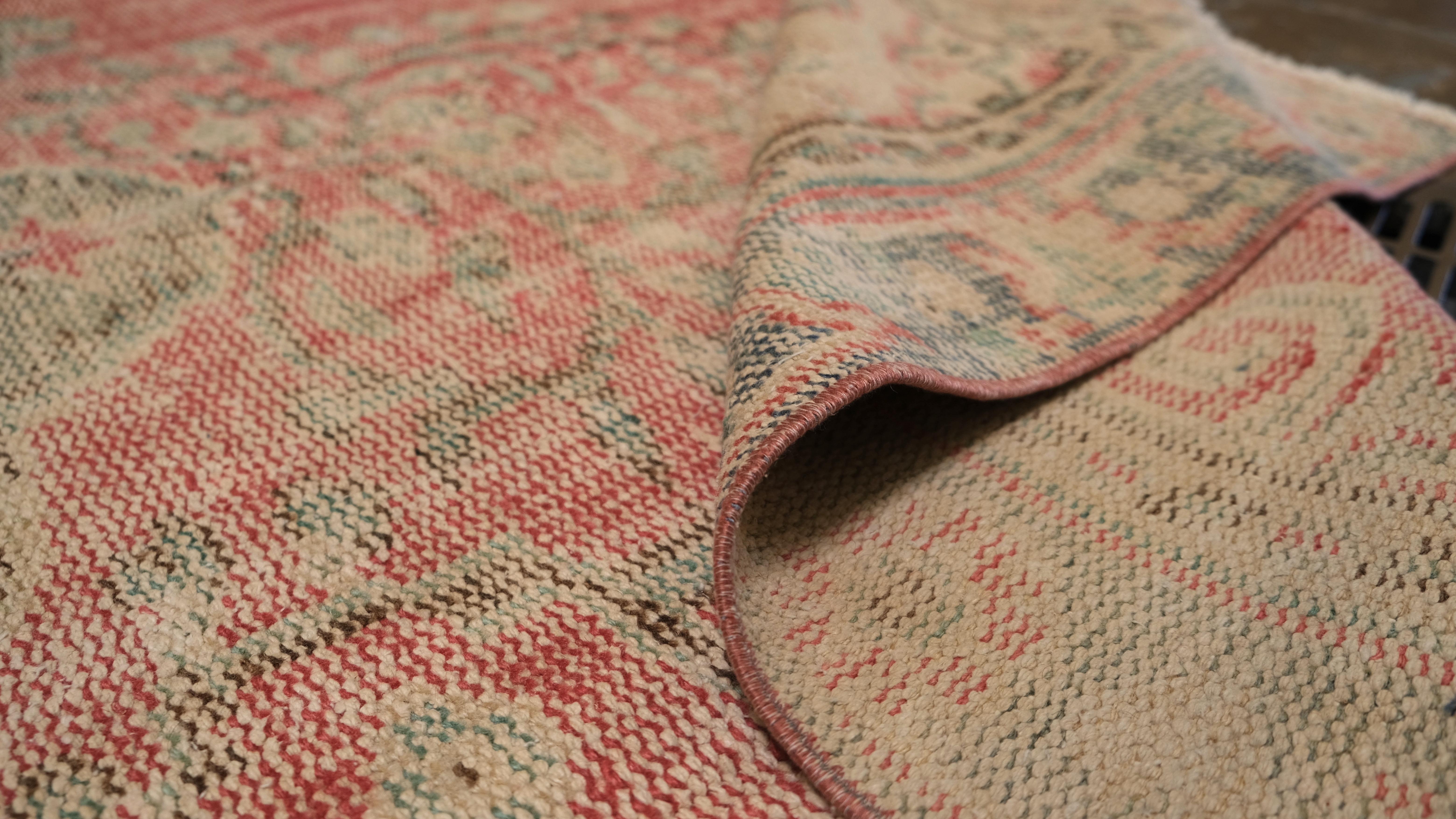 Aggiungi un'eleganza senza tempo alla tua casa con questo tappeto vintage in lana annodato a mano, caratterizzato da un classico disegno a medaglione nei toni tenui del rosa, del verde e del beige. La finitura delicatamente affilata ne esalta il