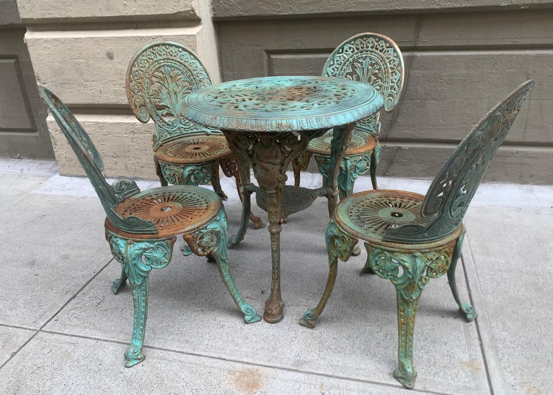 Vintage Victorian five-piece cast iron outdoor patio set. The set has a decorative pattern and the table has figures to the top of the legs.
Table measures: 28 height x 27 diameter.
Chairs measures: 34 H x 17 W x 16 D.
