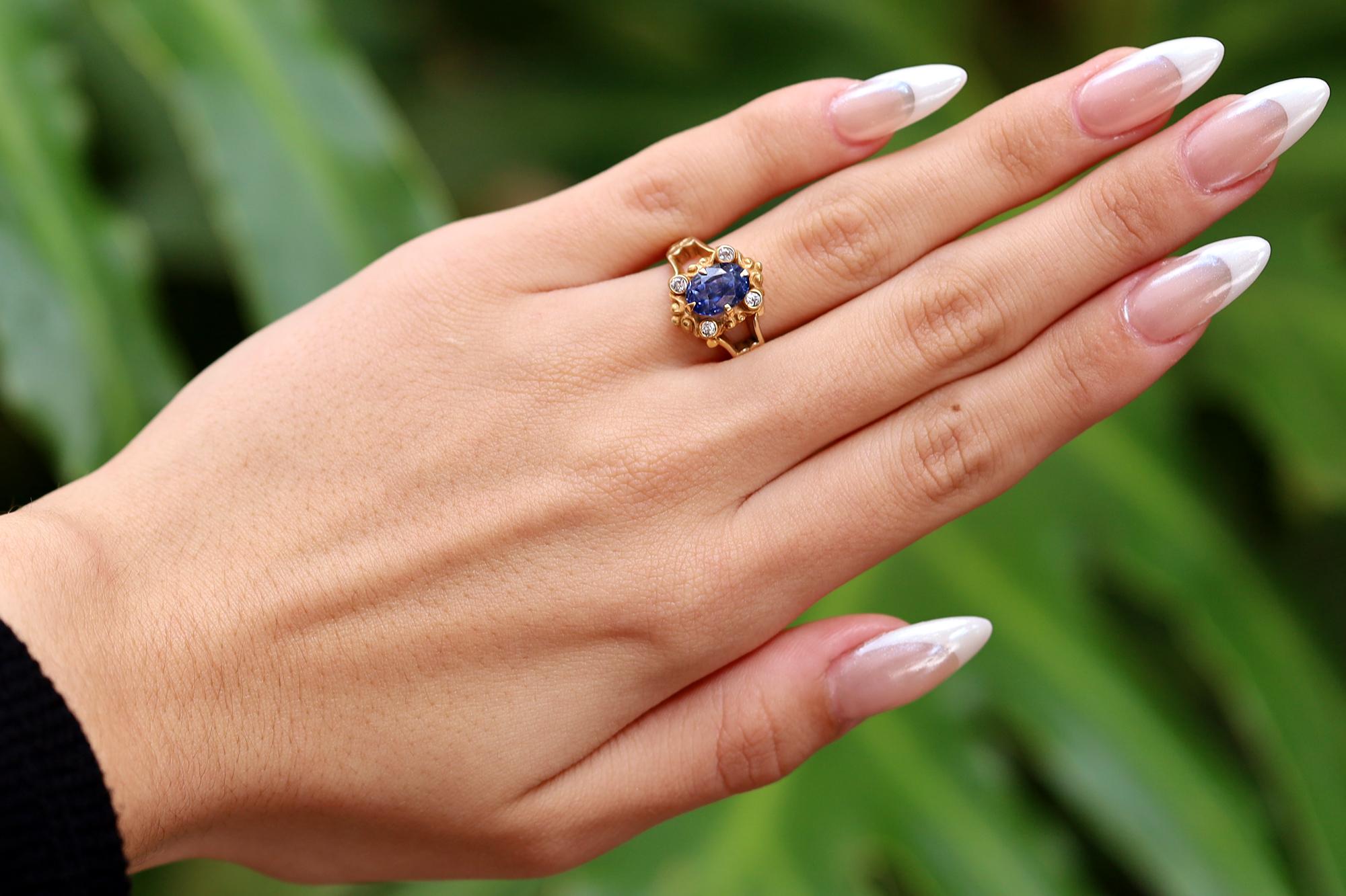 This vivacious Victorian gemstone engagement ring centers on a velvety and vibrant blue sapphire. The well-proportioned oval weighing 2.28 carats is held within a scrolling filigree mounting adorned with 4 sparkling diamonds. For a non-traditional