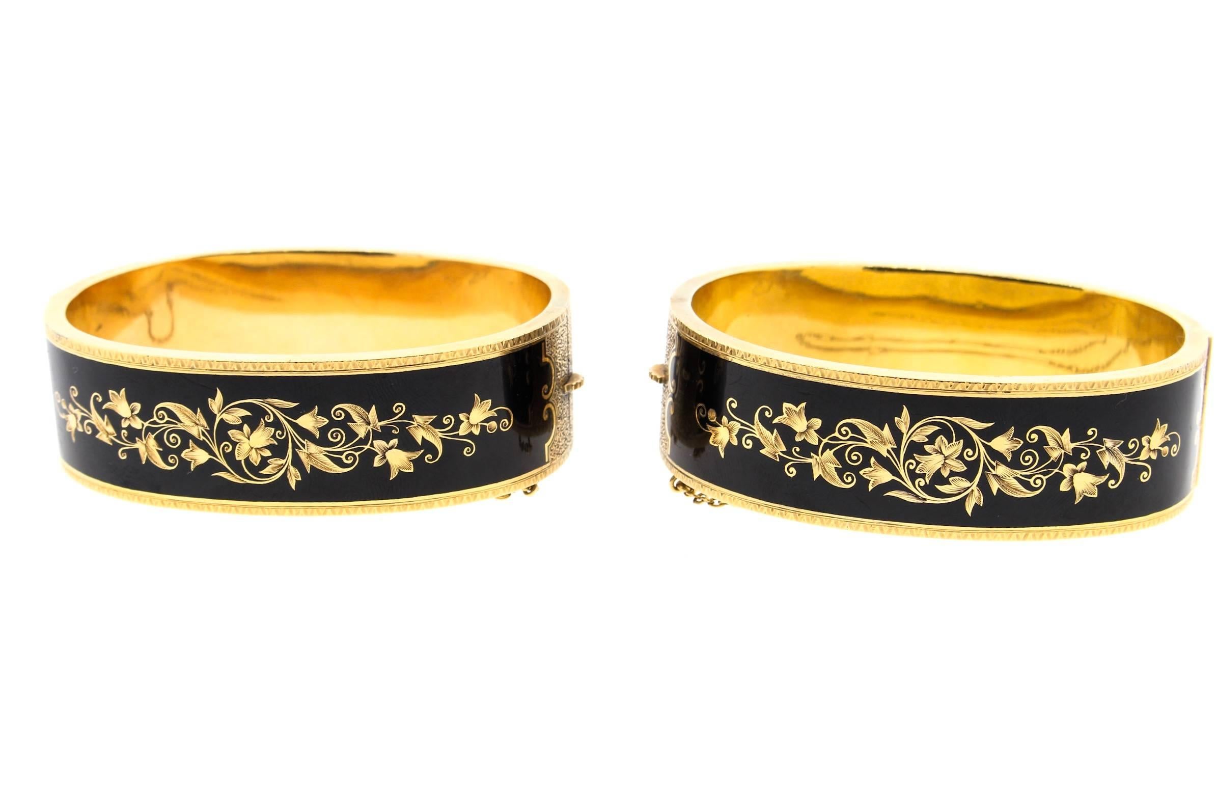 A fine pair of American Victorian black enamel mourning bangles circa 1890.  This 14k gold pair is oval and hinged, with a chain safety.  One side of the bangle has gold tracery scroll work, and the other side has gold tracery floral and leaf