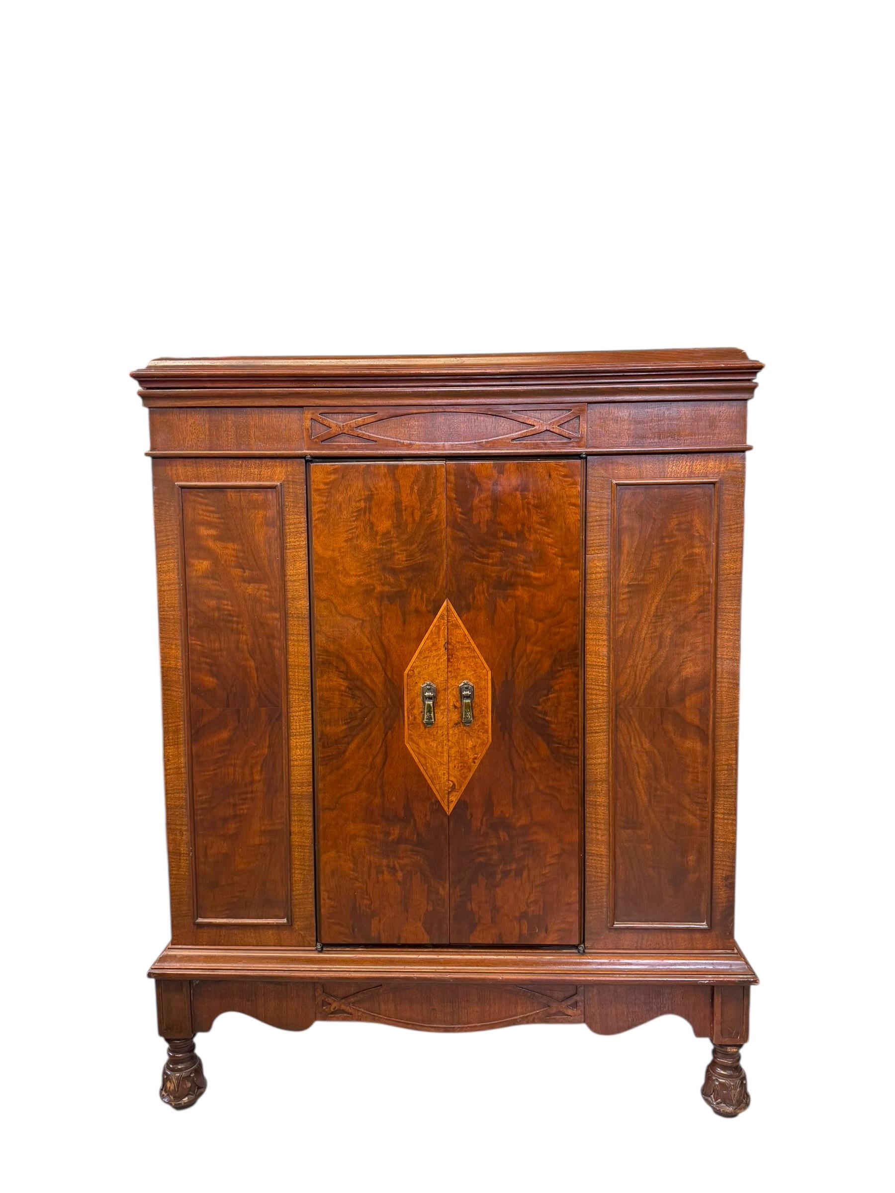 Este mueble presenta características del estilo victoriano, popular en el siglo XIX. La influencia victoriana es evidente en sus ornamentadas patas talladas, la chapa de madera burlada, las incrustaciones geométricas en las puertas y el rico acabado