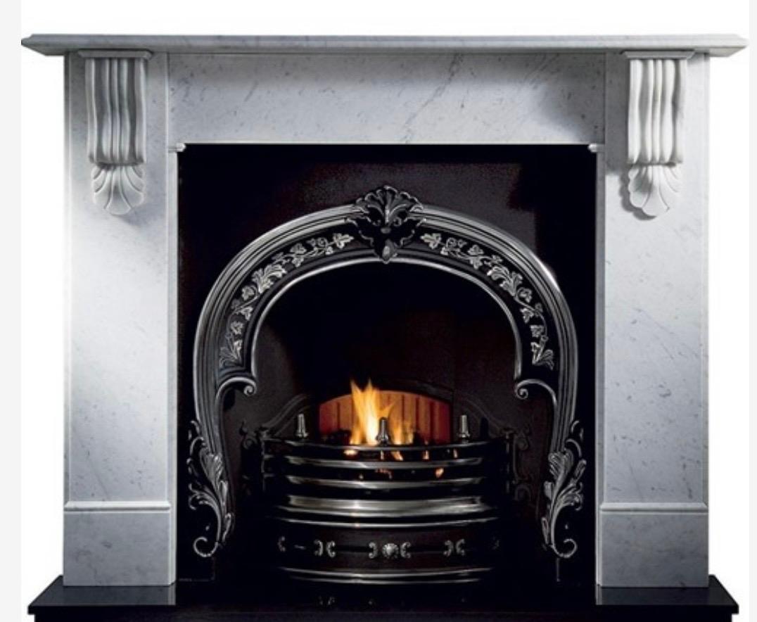 A large sized vintage Victorian style fireplace surround in softly colored Carrara marble. A generous scalloped shelf sits over an unadorned frieze, flanked by a symmetrical pair of well carved corbels and under shells, with moulded capping above,