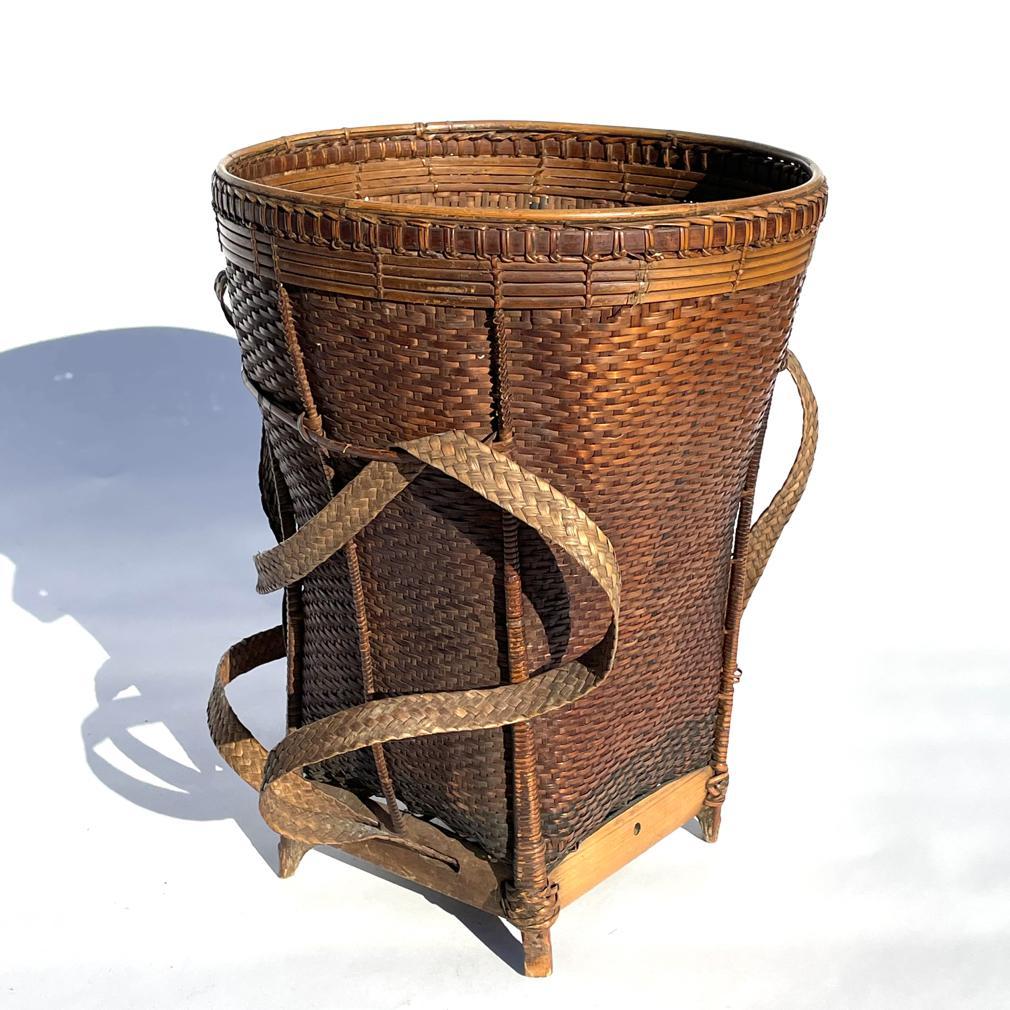 Vintage Vietnamese Backpack Basket. A woven form starting with a square bamboo base tapering up to an open round sturdy mouth with a a smooth interior surface, specifically used in the delicate hand harvesting of tea leaves. The basket weave with