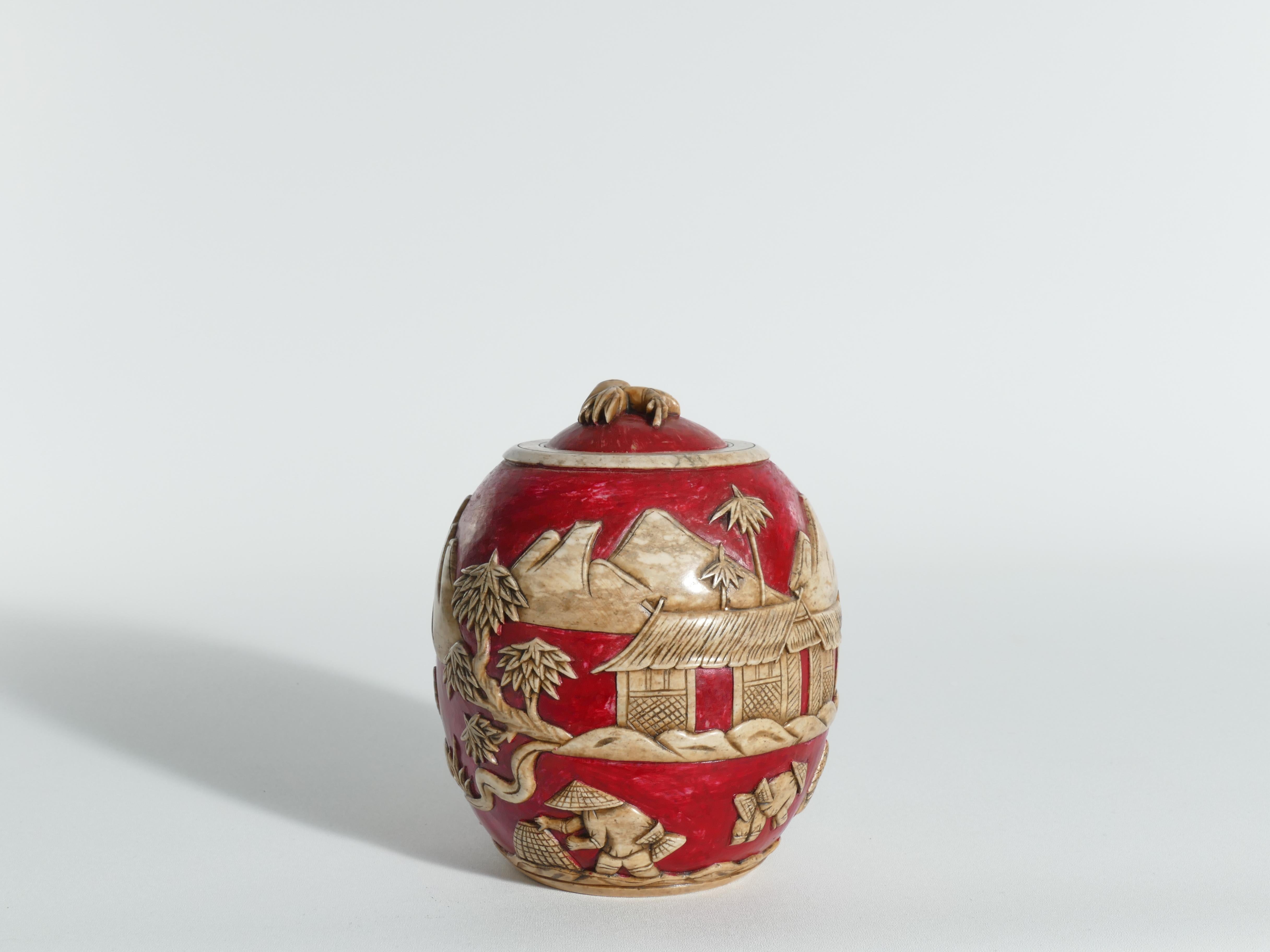 A very beautiful and decorative Vietnamese deep red colored hand carved soapstone lidded jar.The carved details depicting a landscape with workers, a house, trees and mountains are amazing! Since it is made of stone, it is really heavy.  