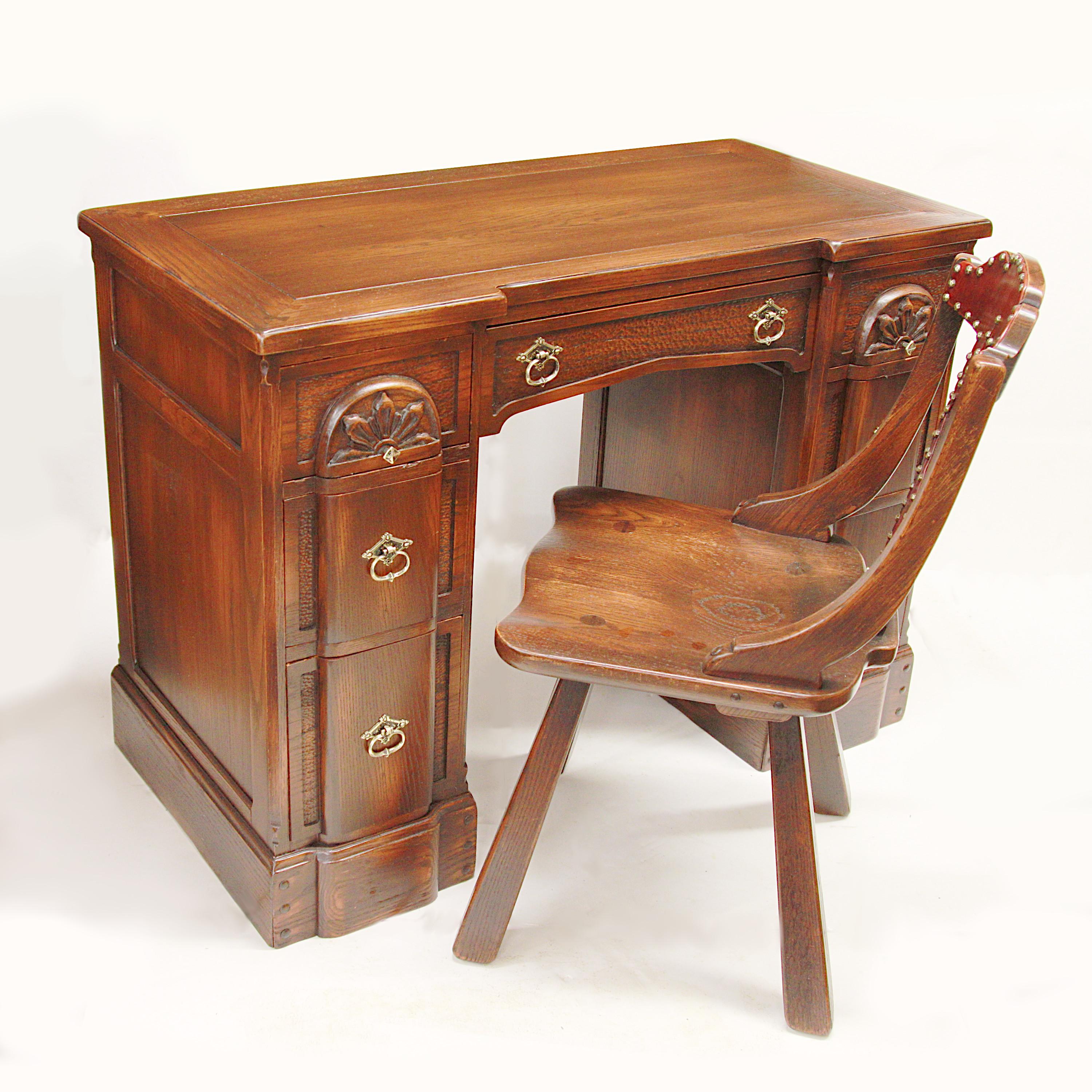 Excellent vintage writing desk in the Viking Oak style by the Romweber Furniture Co. of Batesville, IN. This charming desk features wonderful relief carved details, solid oak construction, and solid brass hardware. Desk is paired with a matching