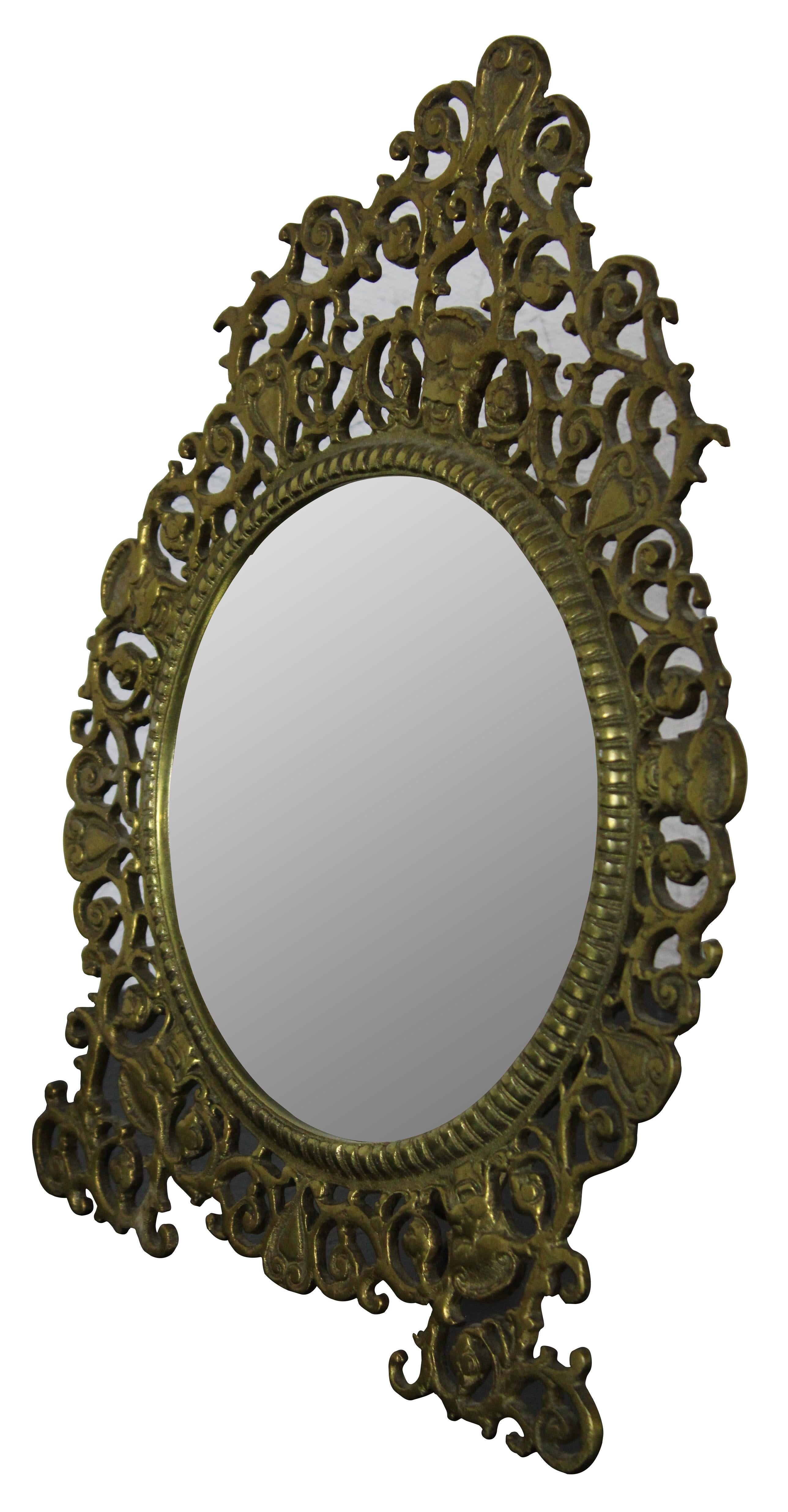 Vintage gilded brass vanity mirror by Virginia Metalcrafters with swirling baroque styling around a round mirror. Marked VM 14-1 on reverse.

Measures: 9.5” x 4” x 12.25” / Mirror - 6.25” x 6.25” (Width x Depth x Height).