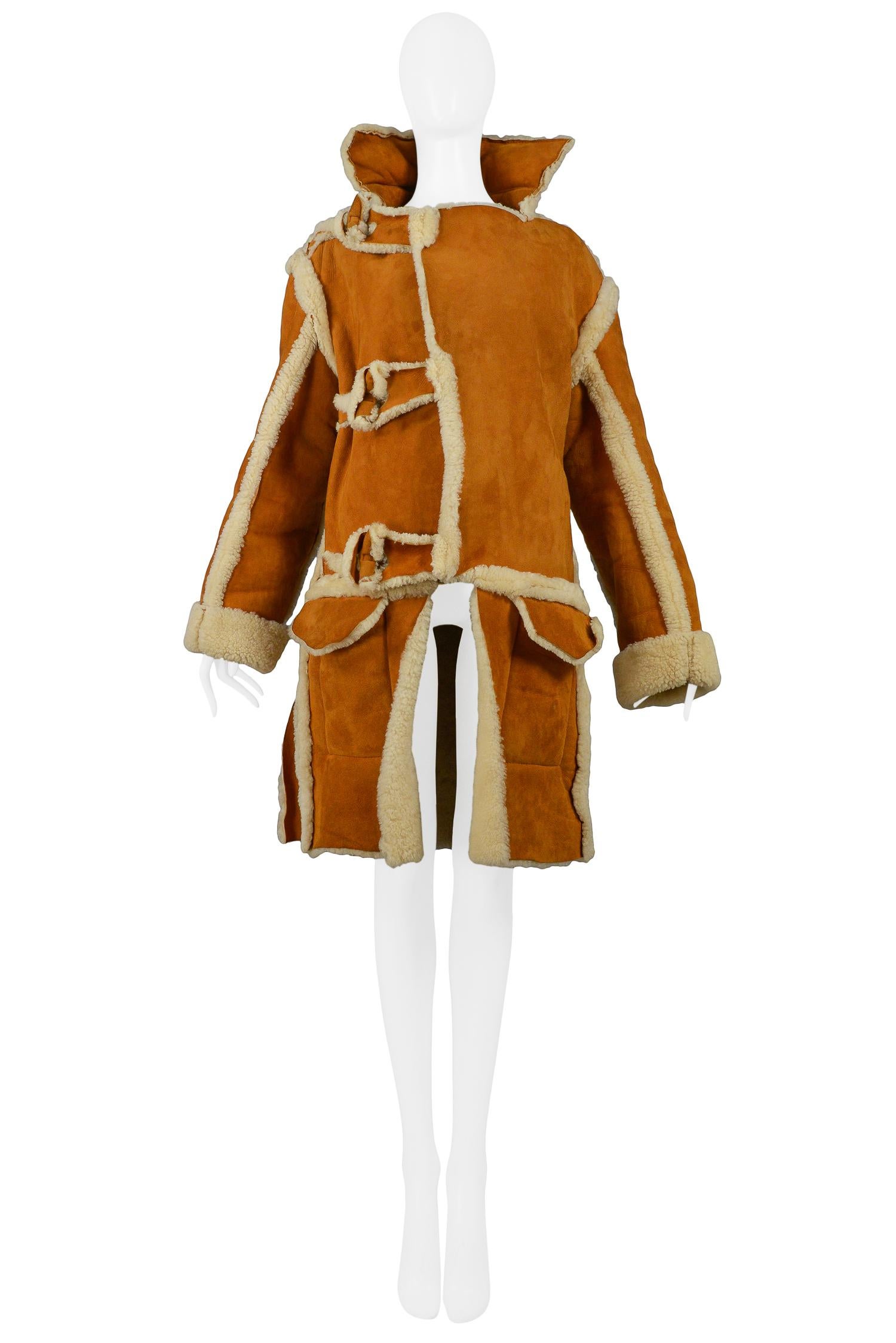 Vintage Malcolm McLaren unisex brown buffalo shearling coat with tan suede exterior featuring a stand-up collar, front pockets, shearling toggles and panels. This coat was done in the style of the World’s End collection he did with Vivienne, but he