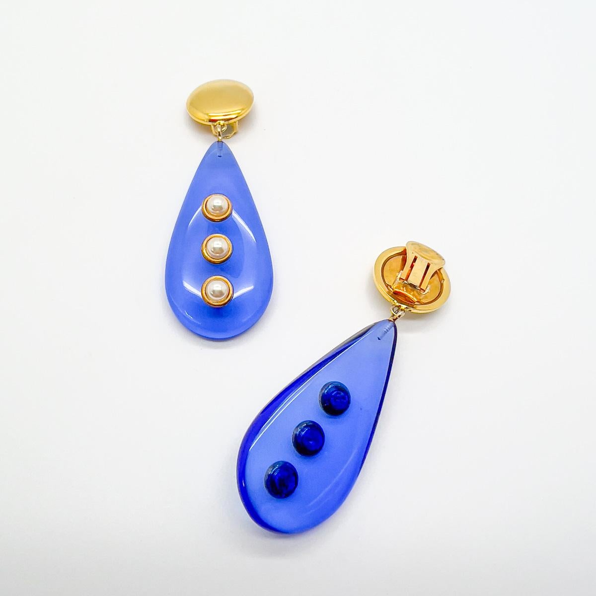 A striking pair of Vintage Vogue Bijoux Drop Earrings. Meticulously crafted the lavish blue teardrop adorned with half pearls is a breathtaking style statement from this exquisite jewel House.
The Italian jewellery brand Vogue Bijoux spans about