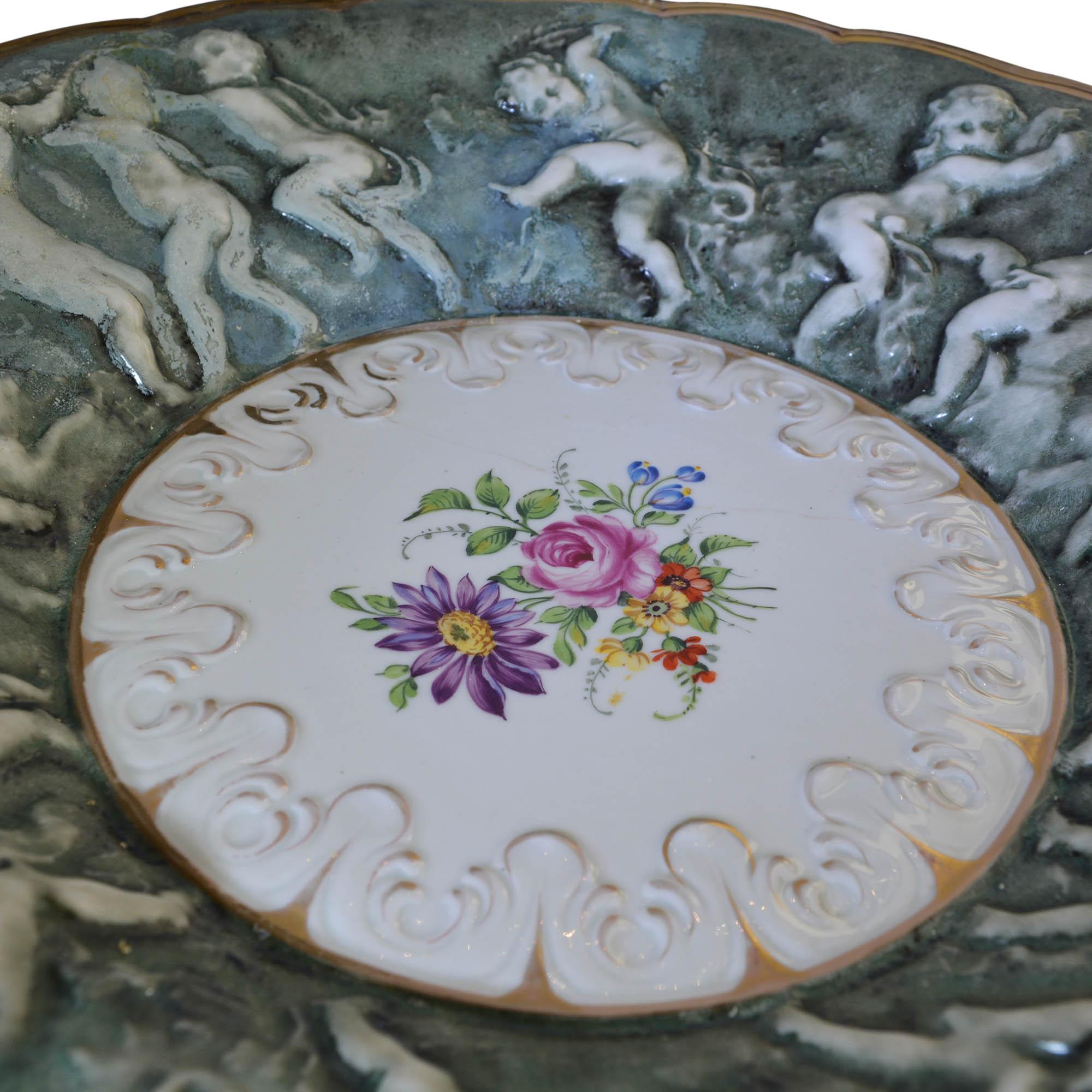 Vintage Von Schierholz bowl or platter has 14 putti dancing around the scalloped rim and features a centre floral design. The heavily three dimensional detailed rim is green with the centre a white porcelain. Gold gilt highlights.