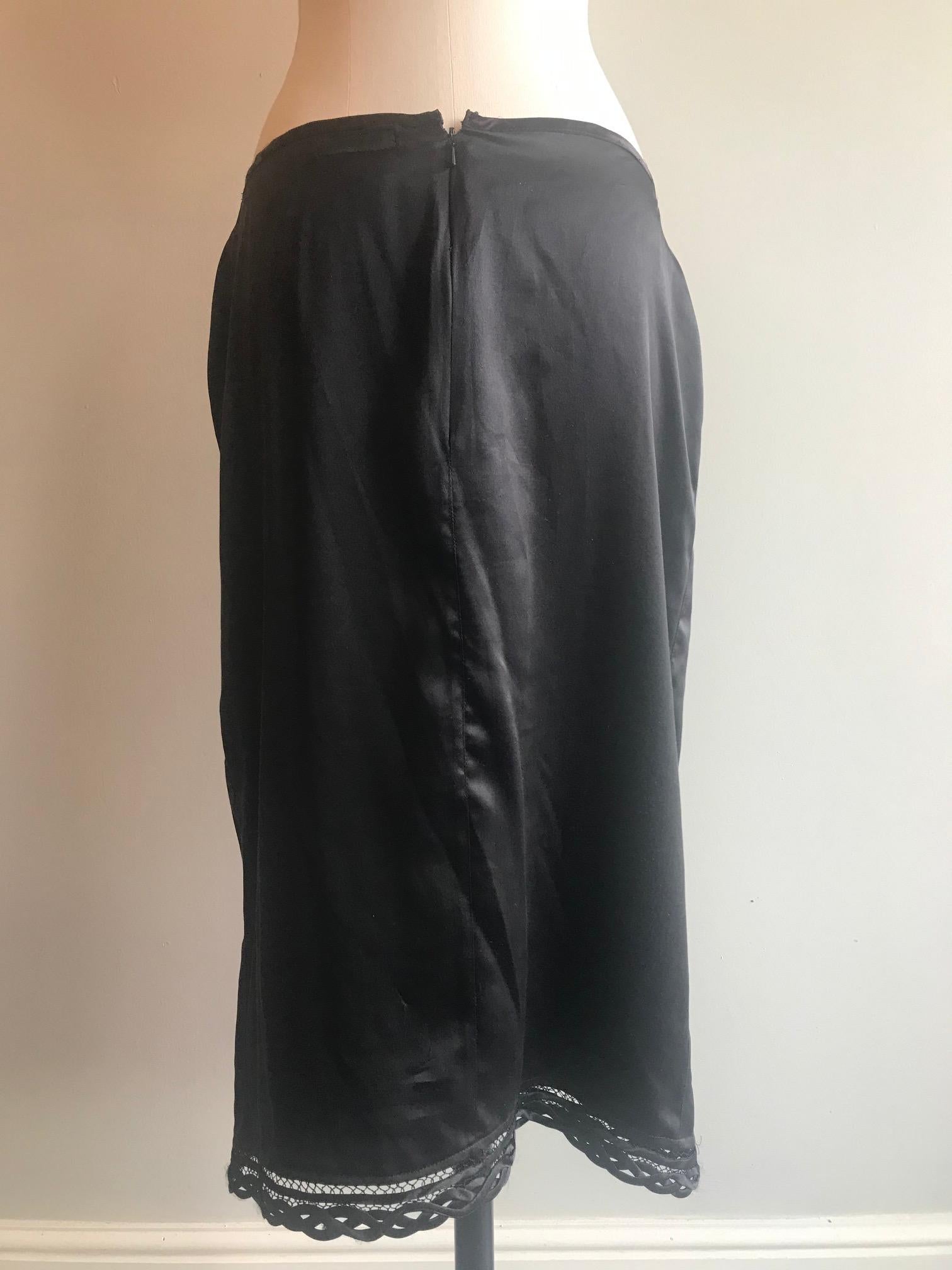 Vintage black silk midi skirt from Voyage Invest In The Original. With silk and lace woven trim at the hemline and along the slit. With single pearl detail at the front. Marked size Large. Made in England. Fabric content: 100% silk. Measurements: