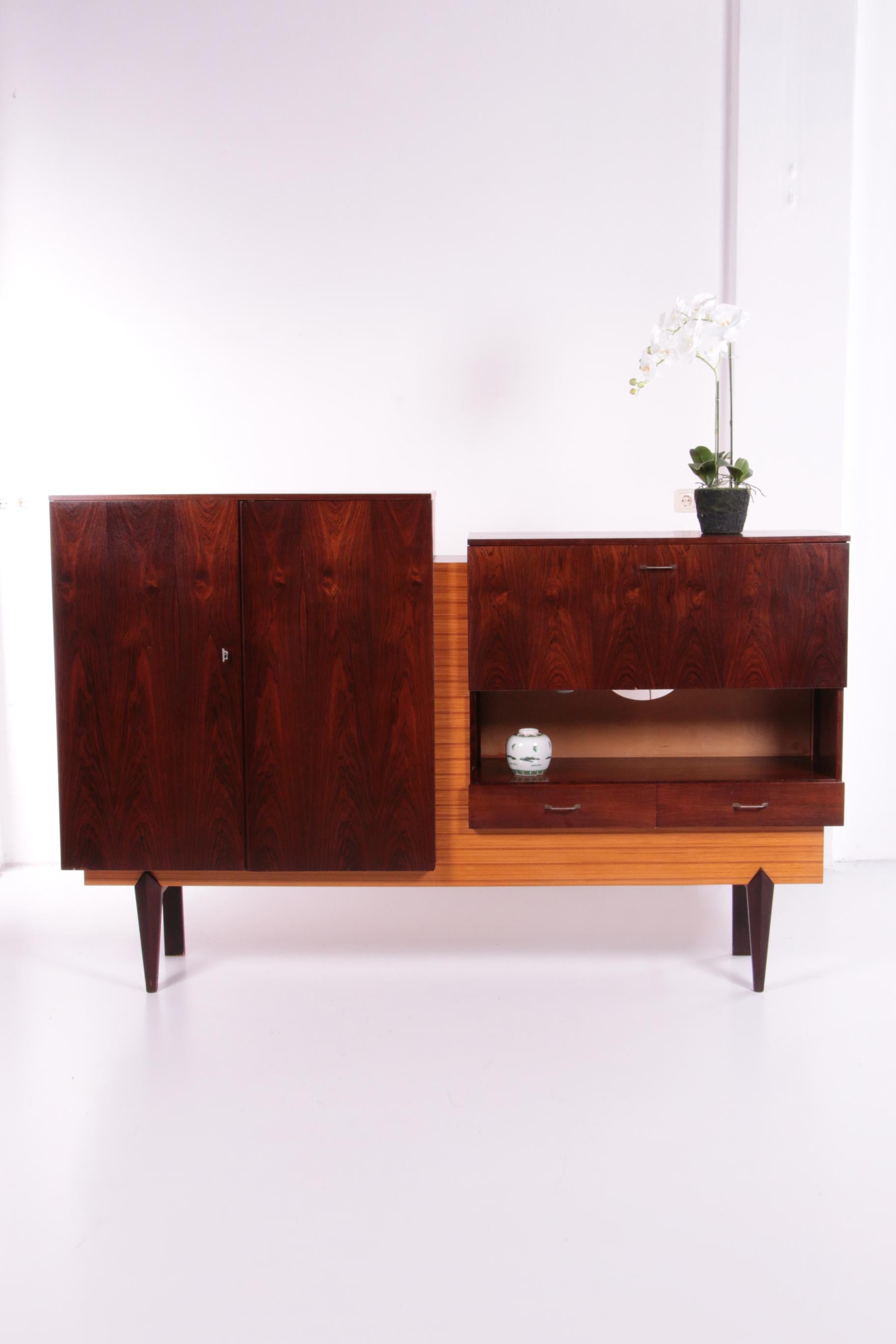 Beautiful vintage wall cabinet made in the Netherlands in the 1960s.

The cabinet is made of 2 types of wood, darkwood, finished with veneer and walnut.

On the left side are large doors with three sturdy shelves.

At the top right of a bar cabinet