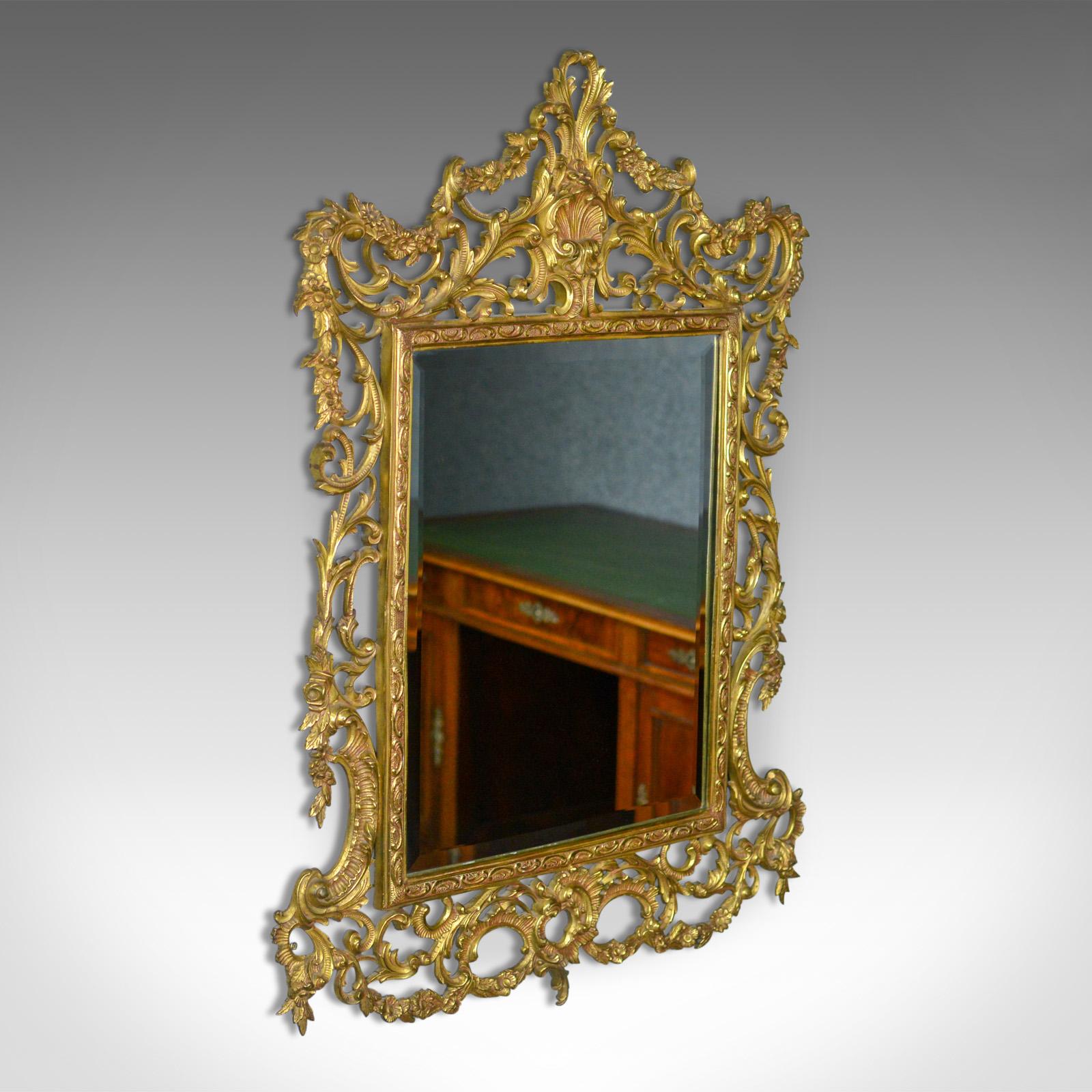 This is a vintage wall mirror, an English piece in the Rococo revival manner dating to the Art Deco period of the 20th century, circa 1940.

An elaborate and elegant Italianate design
Gilt metal frame featuring scrolls, floral and foliate