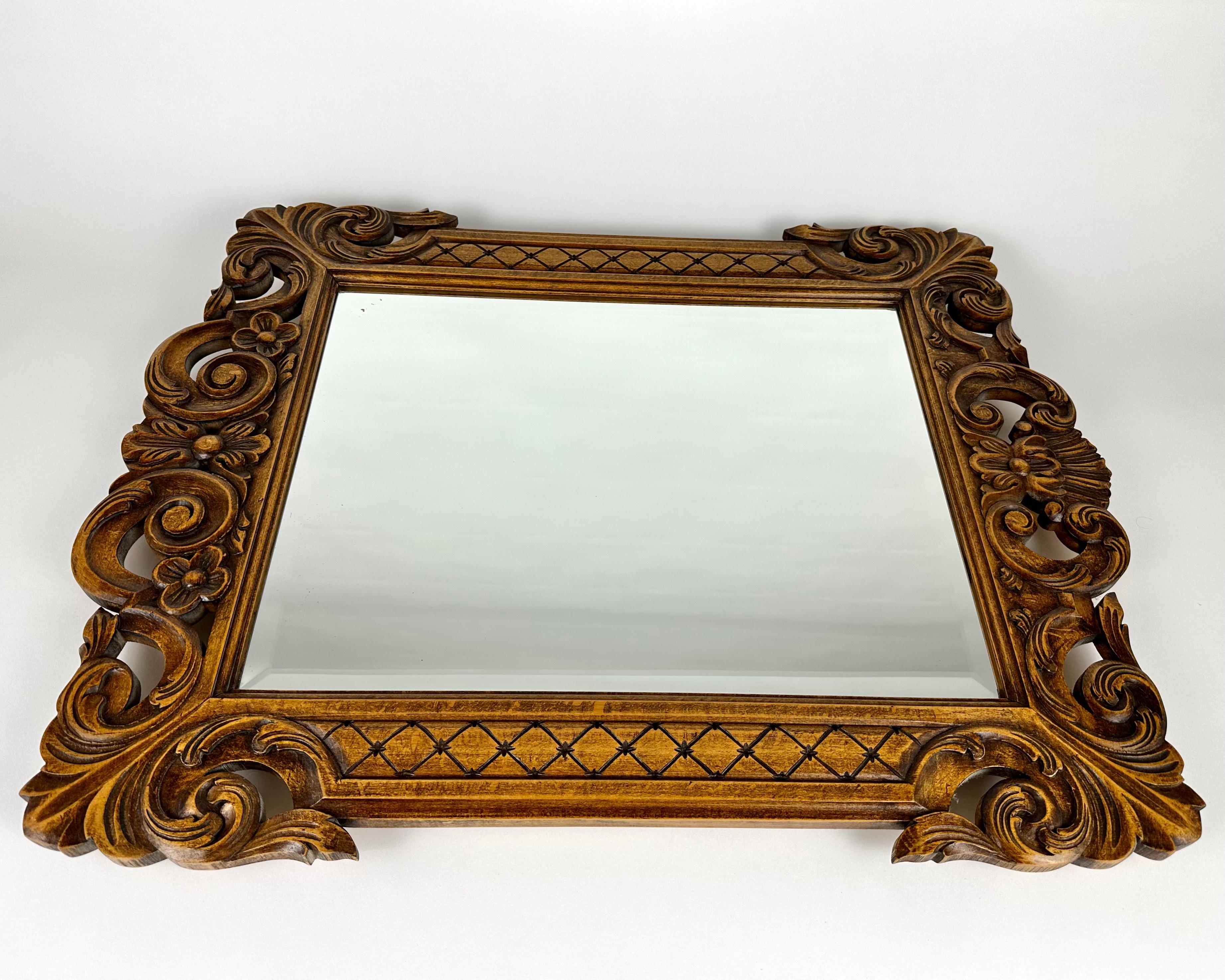Vintage Faceted Wall Mirror in Carved wooden frame, mid-20th century.

The rectangular shaped mirror with pierced scrolled acanthus cresting and flanked by pilasters and floral festoons.

Very detailed and finely carved by craftsmen.

Baroque