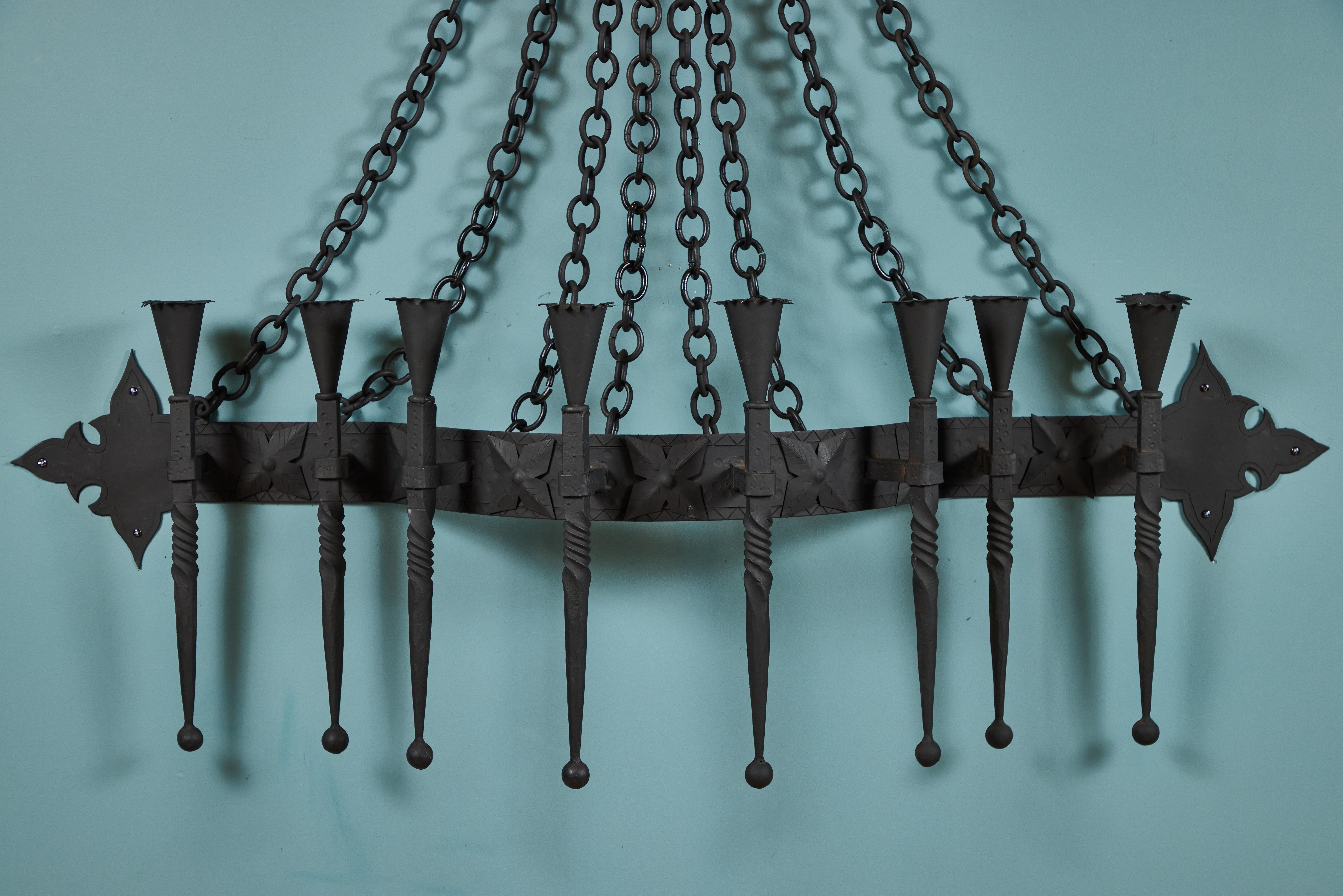 This large vintage wall mounted metal candelabra is made out of iron, the top plaque holds 8 chains that connect to a curved decorative band with 8 candle holders. (New black painted finish)

It is quite handsome and would be spectacular over a