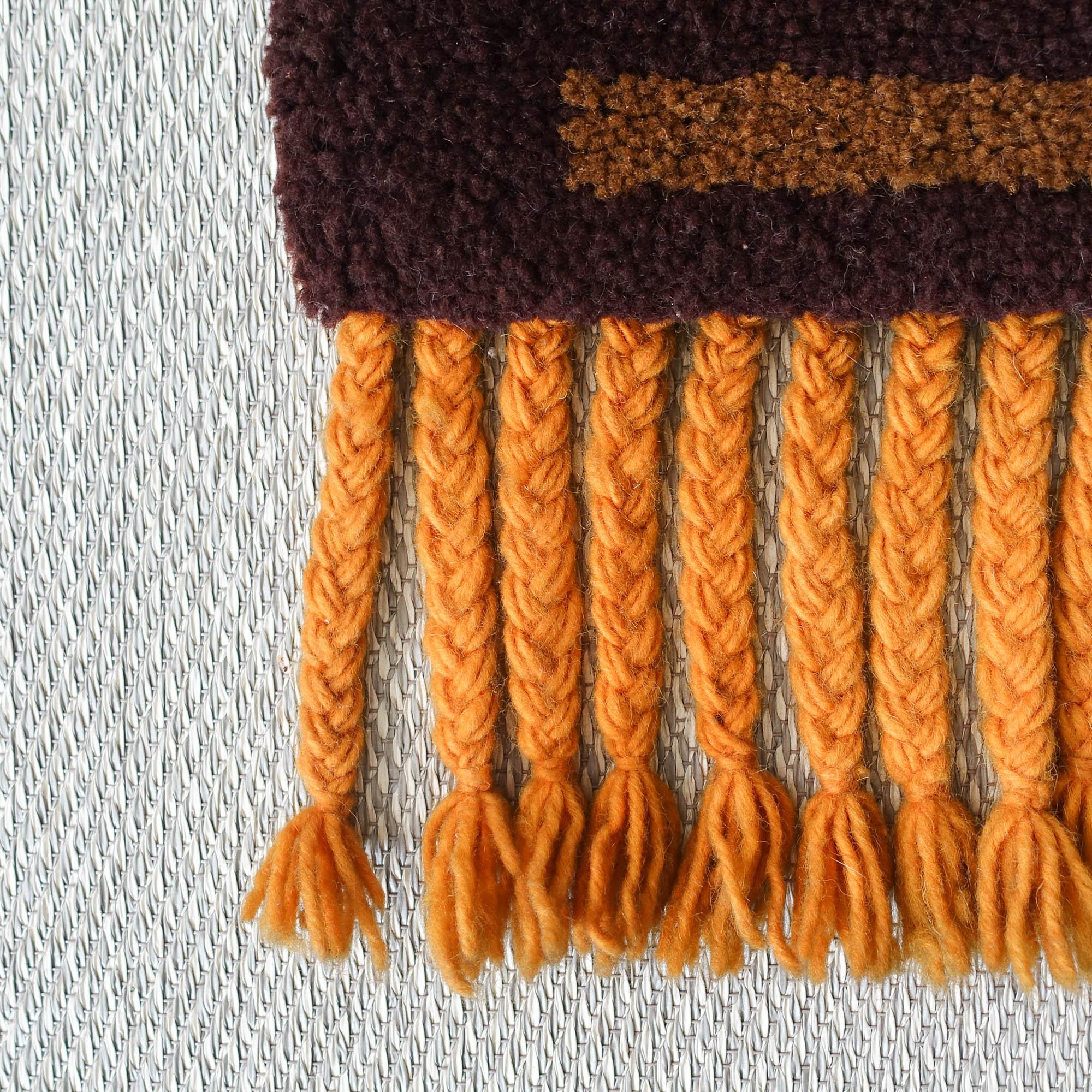 Questo tappeto da parete vintage è stato disegnato e prodotto nei Paesi Bassi, negli anni '60. Rappresenta un albero con le foglie che cadono, nei toni dell'arancio, del giallo e del marrone. È realizzato in lana e presenta una frangia intrecciata