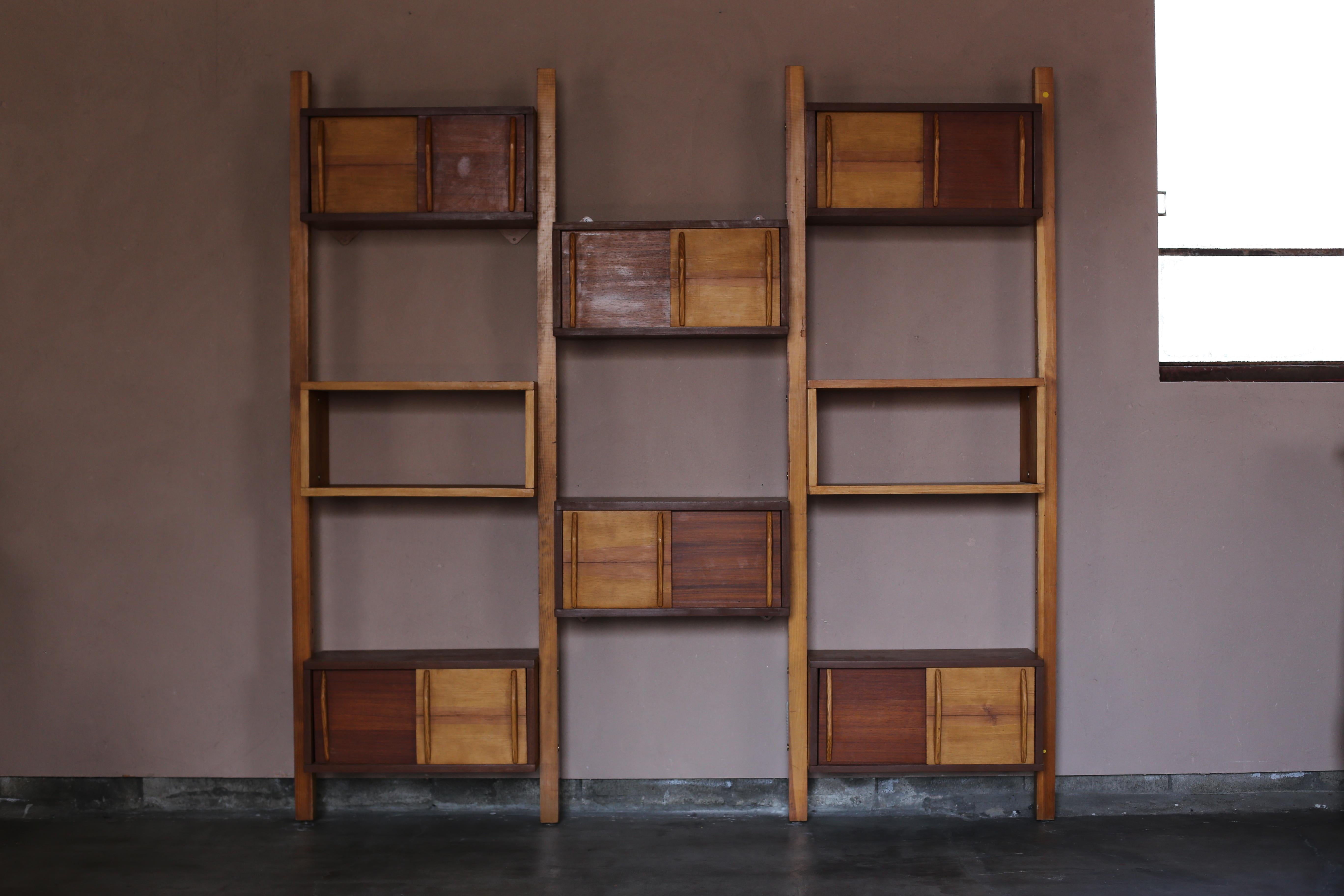 Mid-century modern ’Bibliotheque’, 1970s architect edition, in the style of Charlotte Perriand, Le Corbusier. The wall unit exists out of 4 poles, 6 cabinets, and 2 shelves. A two-tone piece in beech and teak.